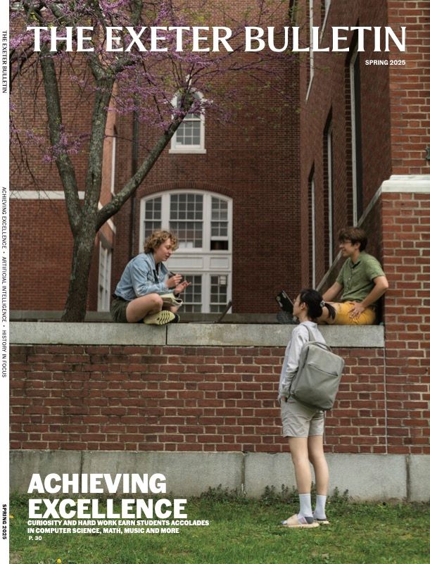 Girl stands talking to two students sitting on a brick wall