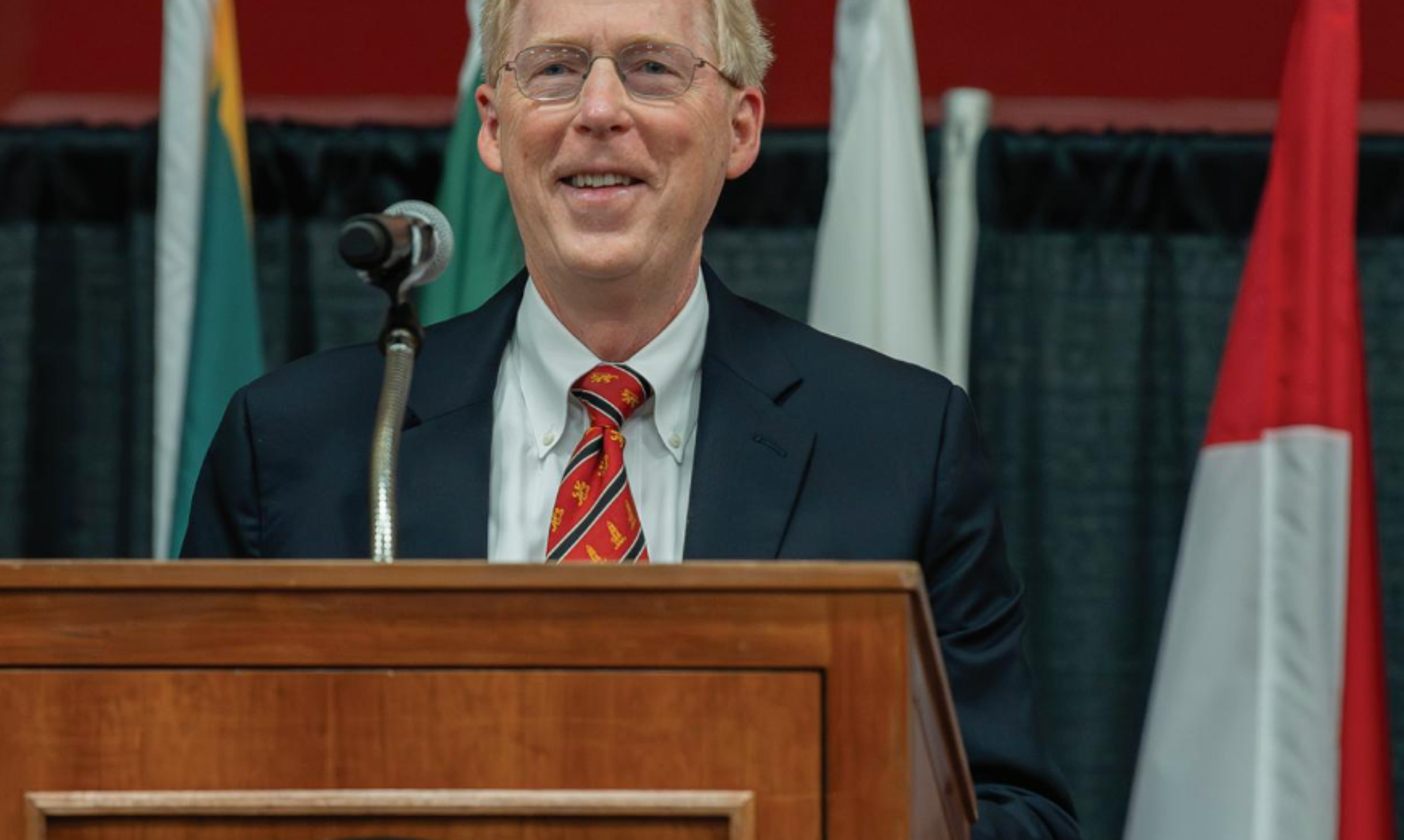 Man with glasses at a podium and microphone.