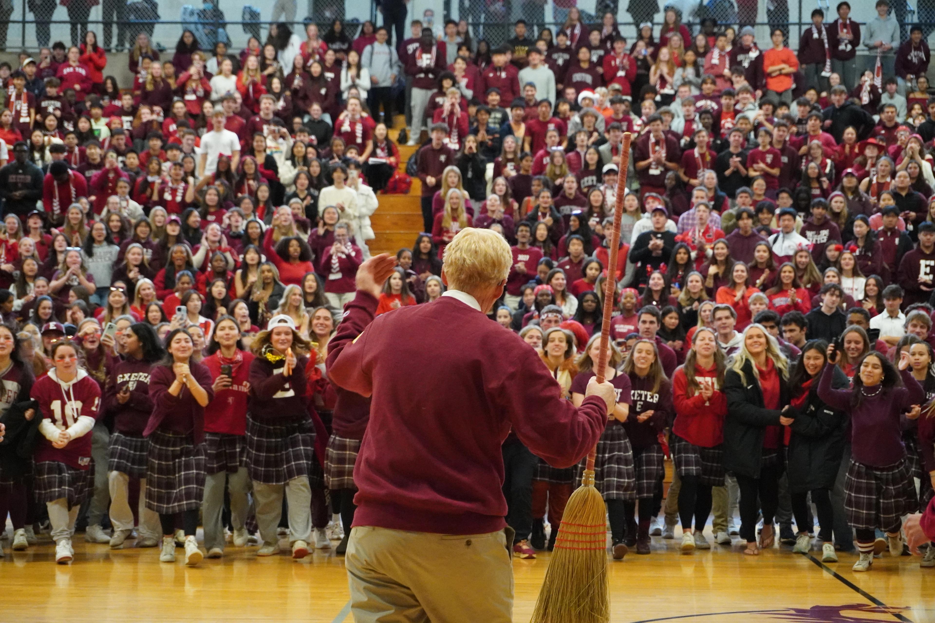 Rawson stands in front of large crowd with broom