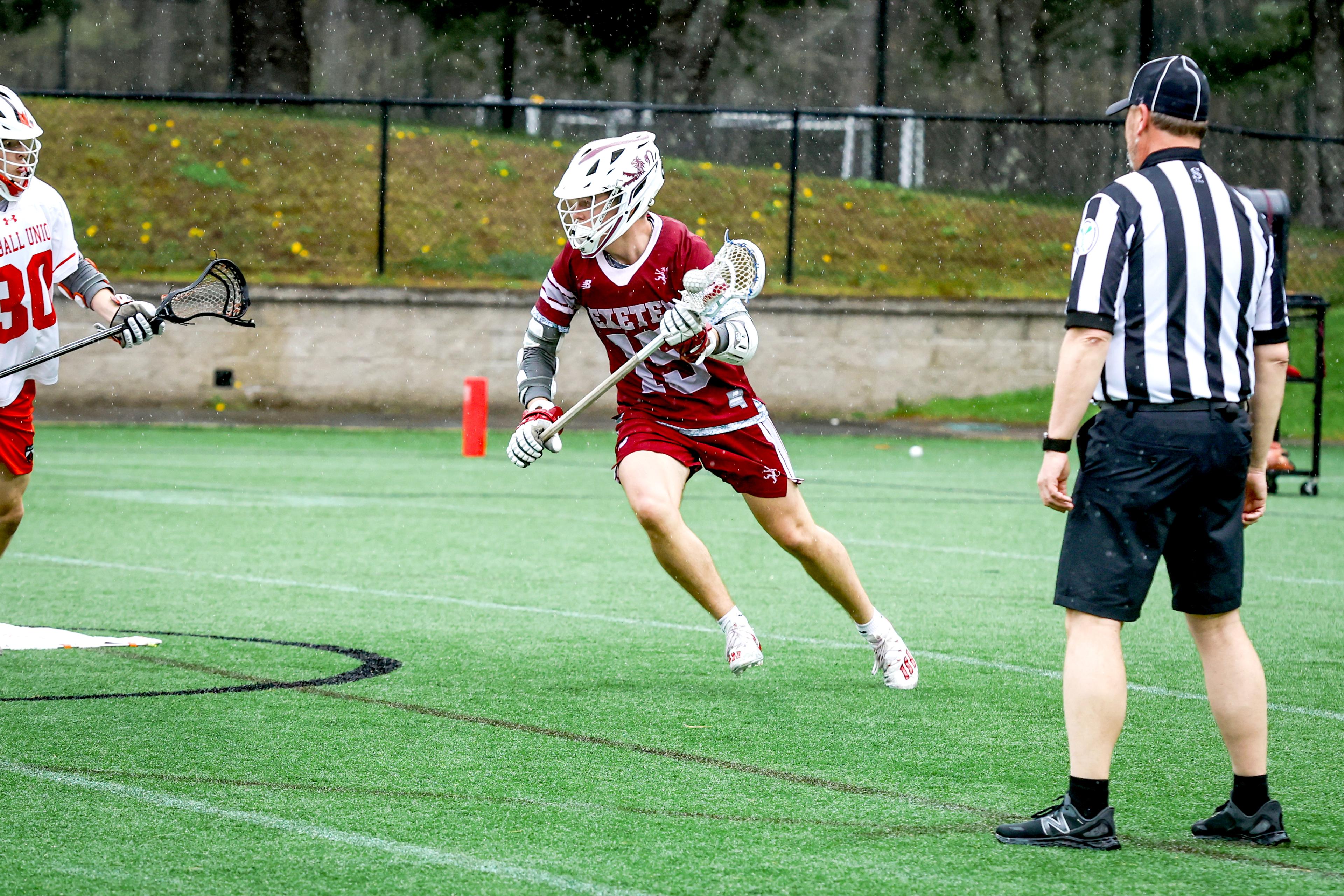Lacrosse player runs while ref stands on field