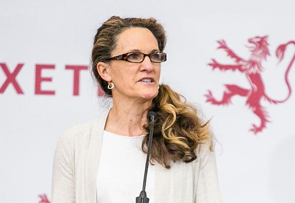 Hilary Hall stands at a podium and speaks to a crowd.
