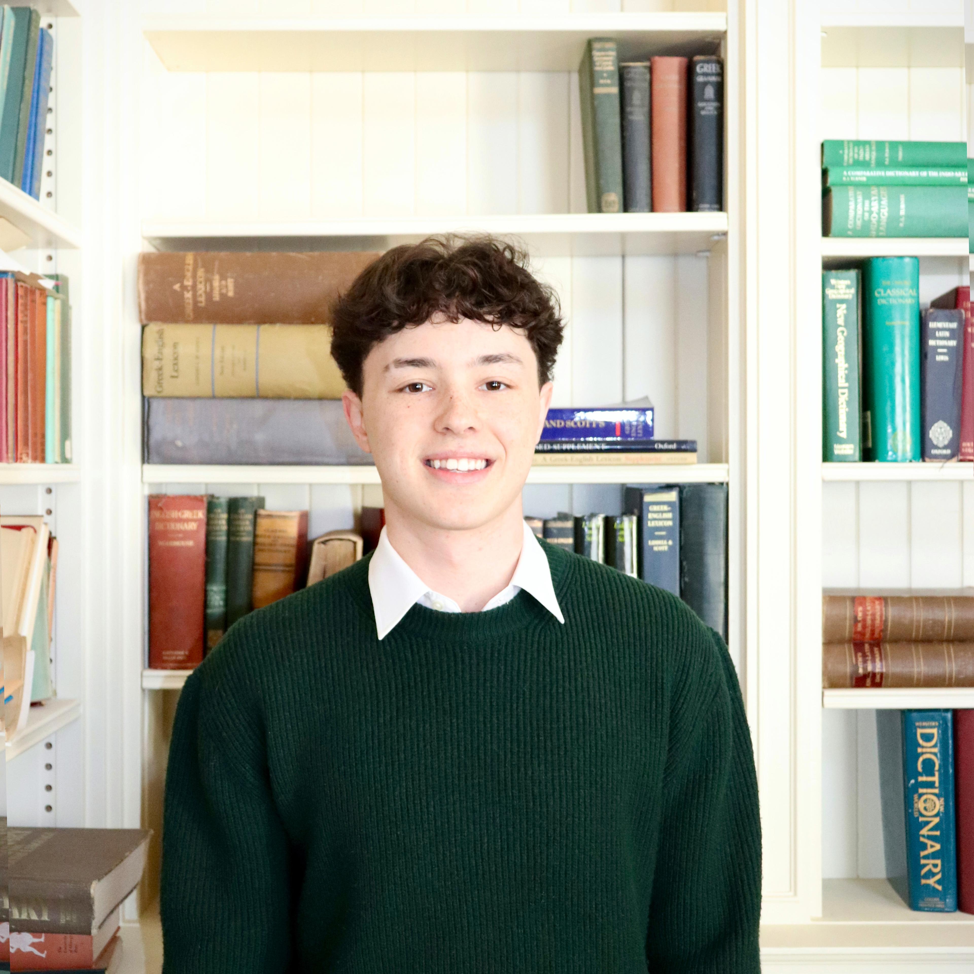 Student stands in front of books in the Davis Library
