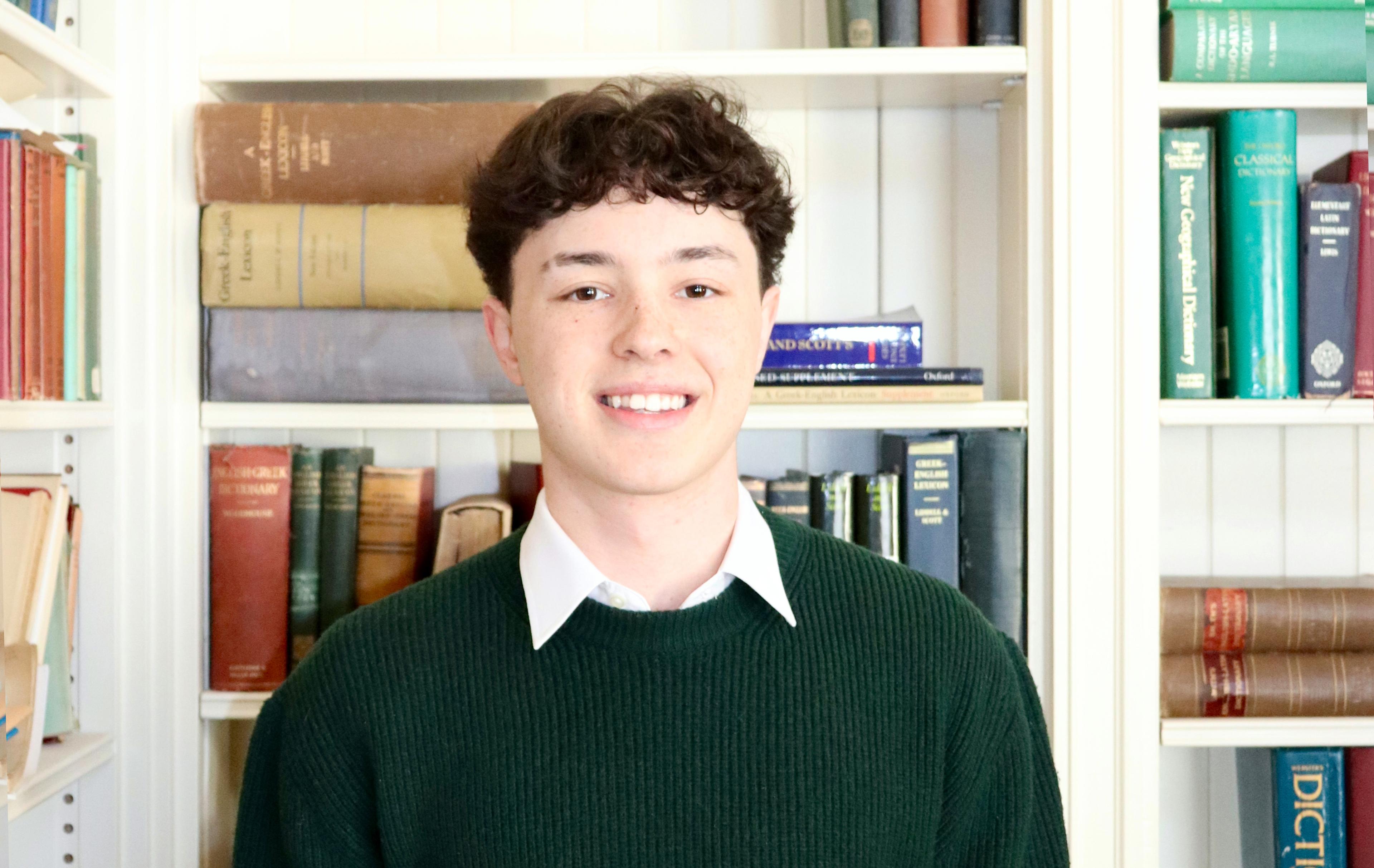 Student stands in front of books in the Davis Library