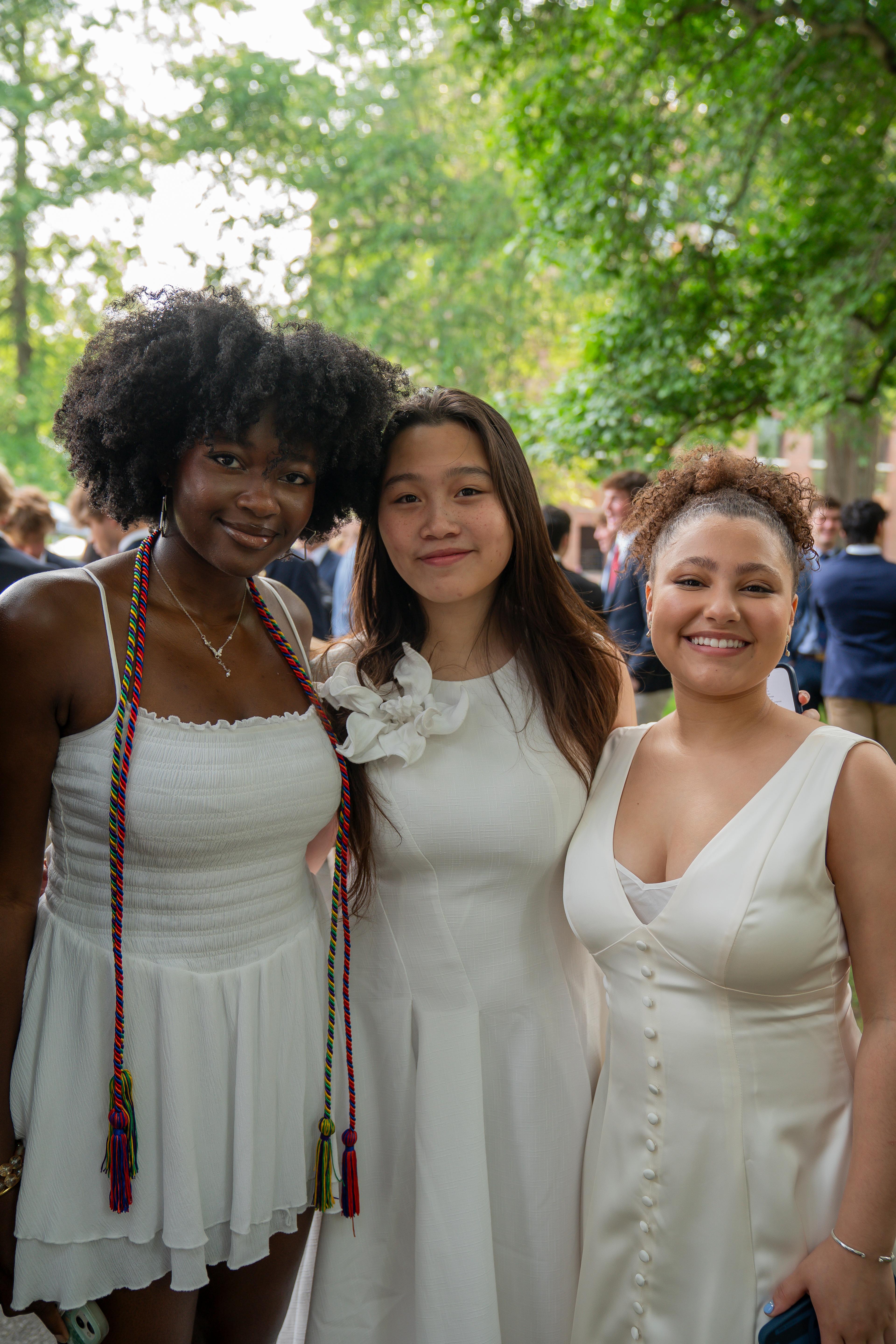 Three girls stand under a tree