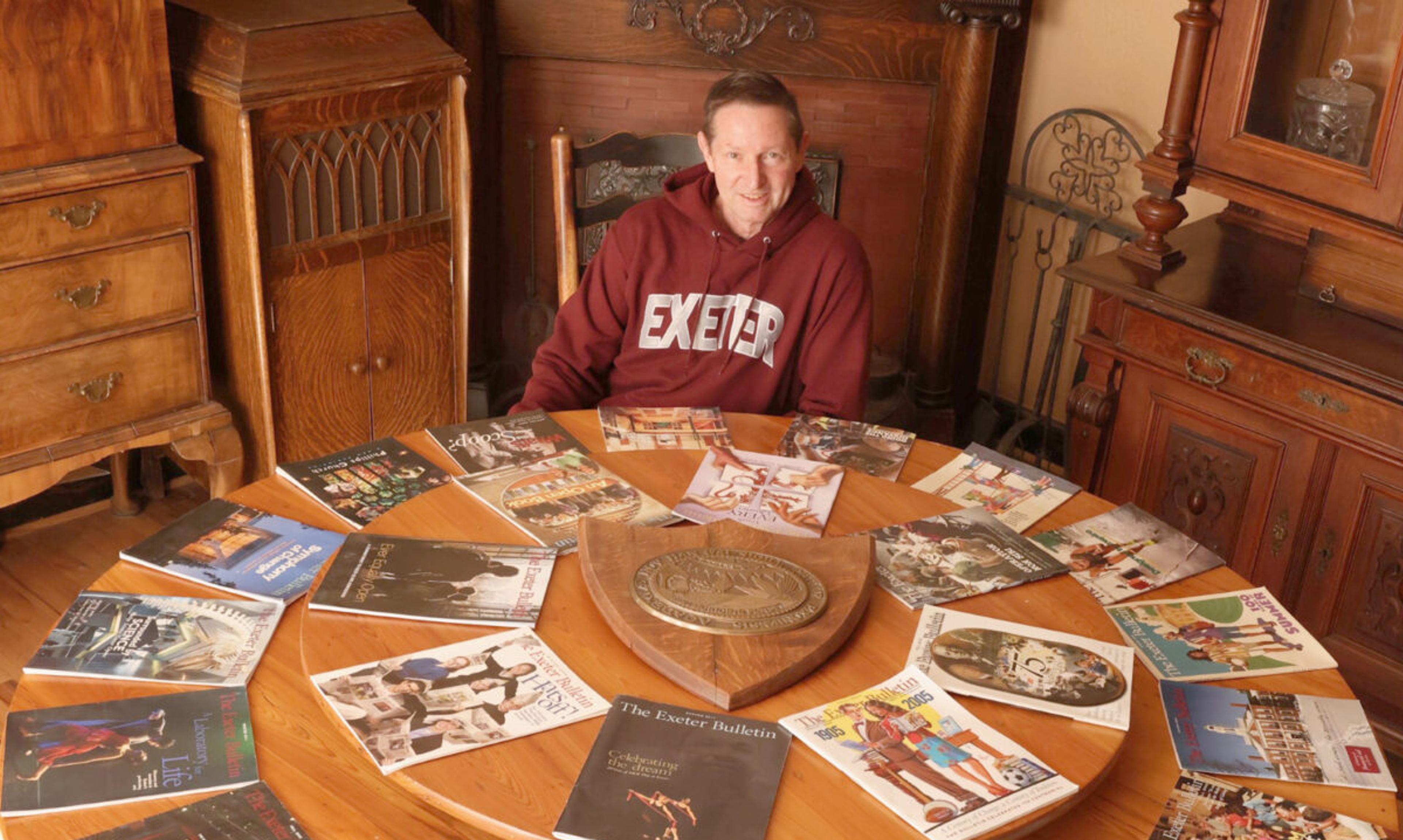 Man sits at table with dozens of Bulletin editions around him