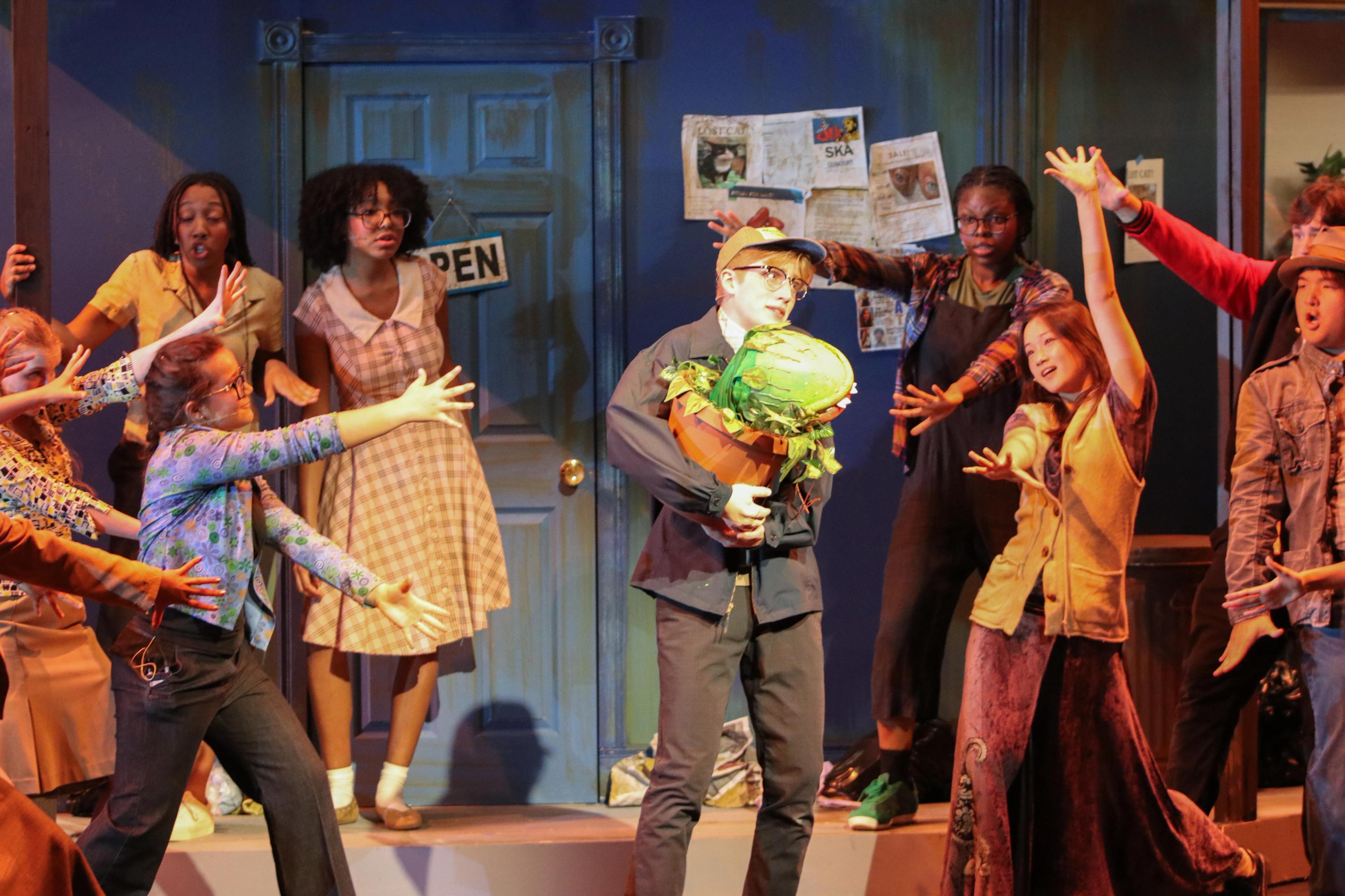 Group of actors sing in musical on stage at Goel Main Stage Theater