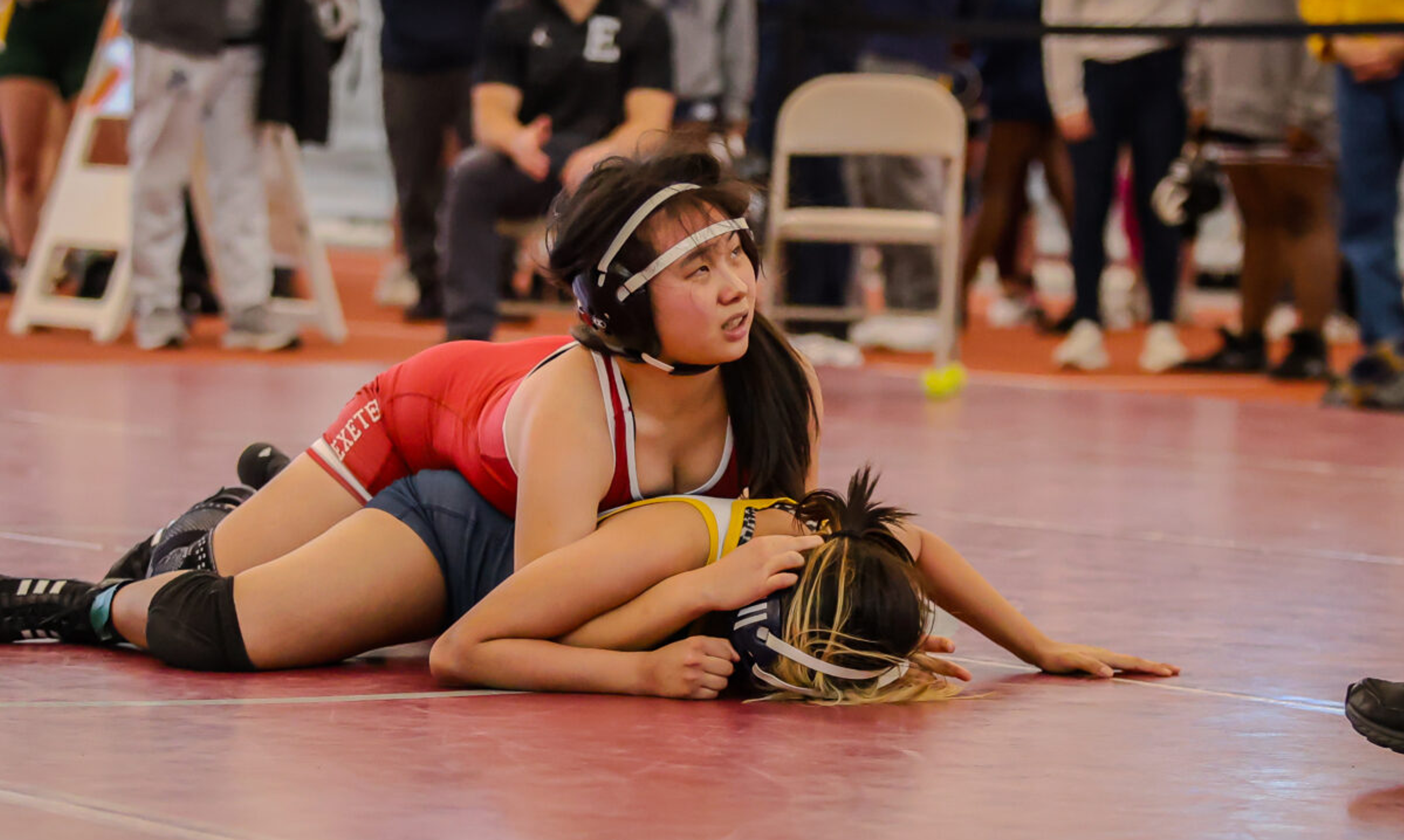 Girl pins another girl down on a wrestling mat