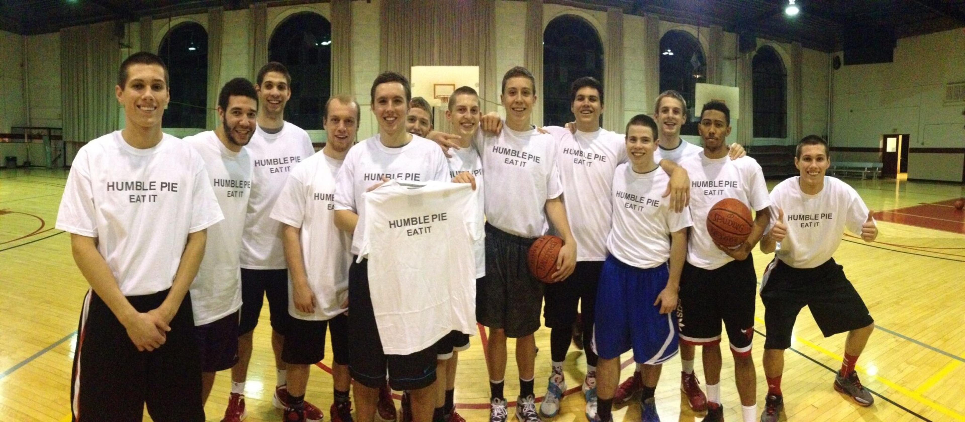 Boys basketball team stands in gym wearing shirts that say "Humble pie eat it"