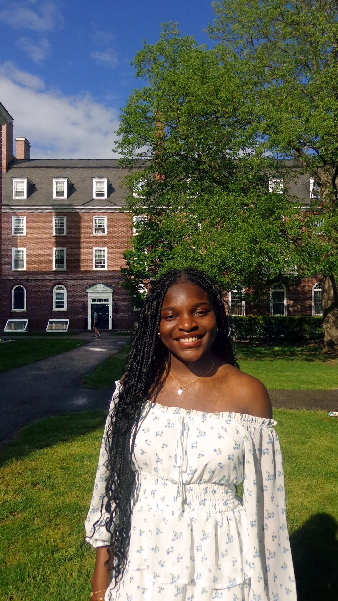 Girl stands in front of red brick building and tree