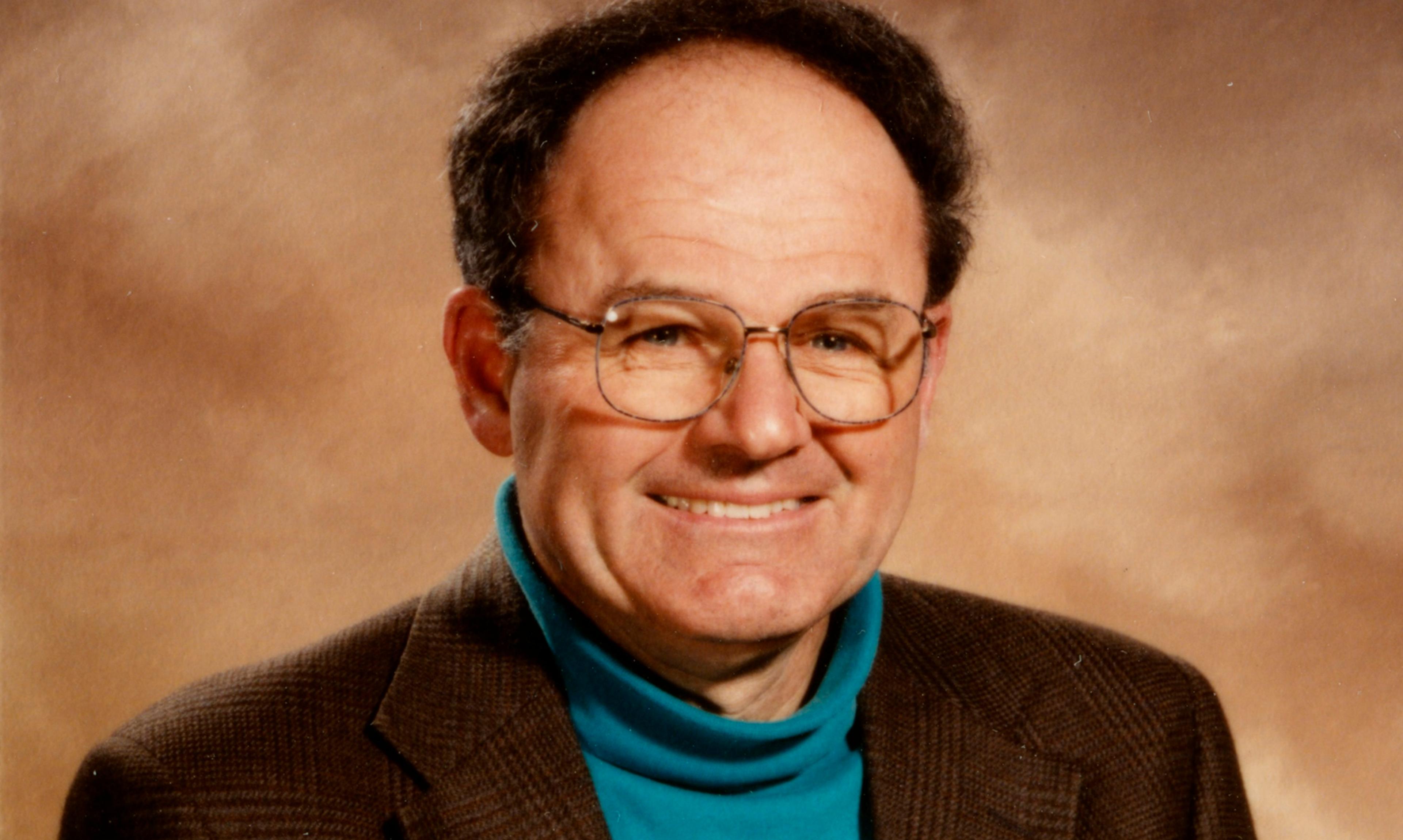 Man in brown suit sits for photo