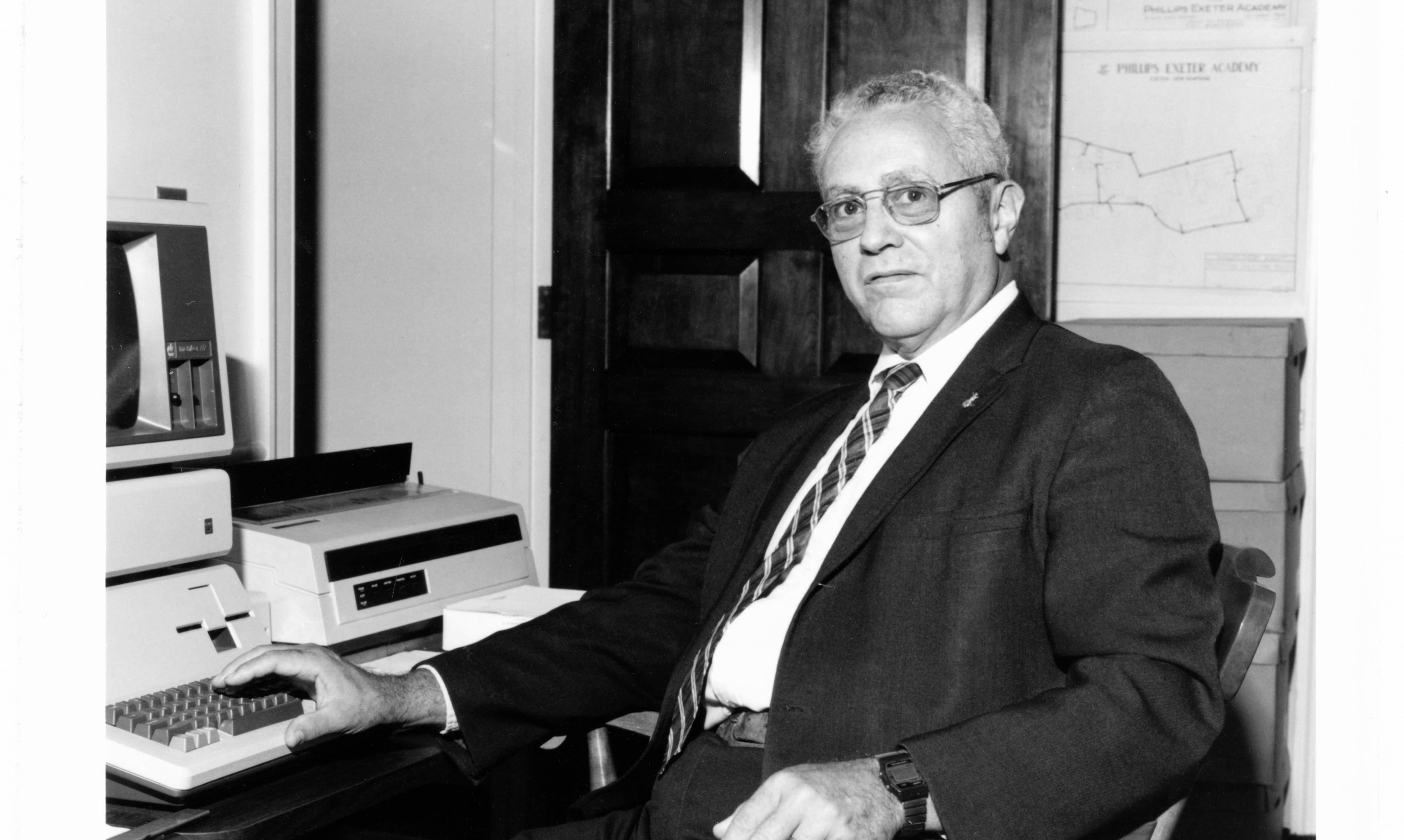 Black and white photo of a teacher sitting at a desk