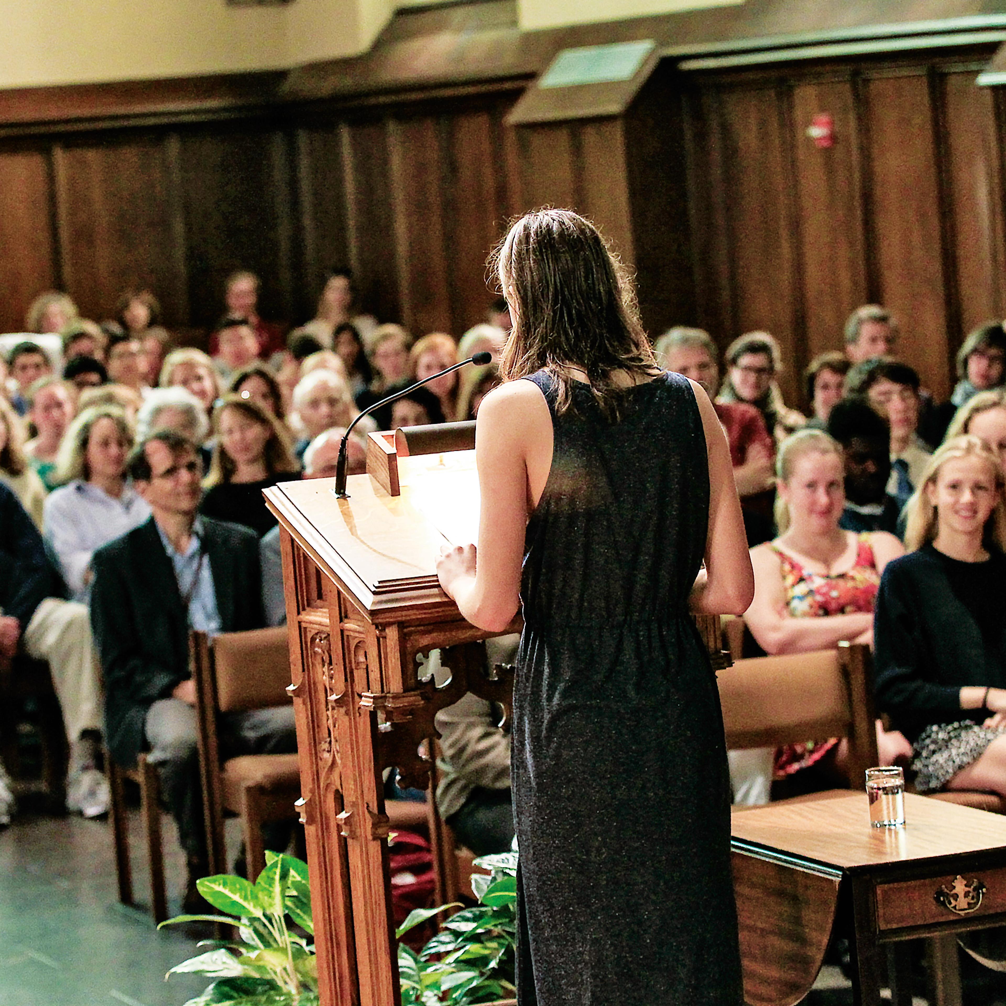 Woman stands at podium in front of a crowd in church pews
