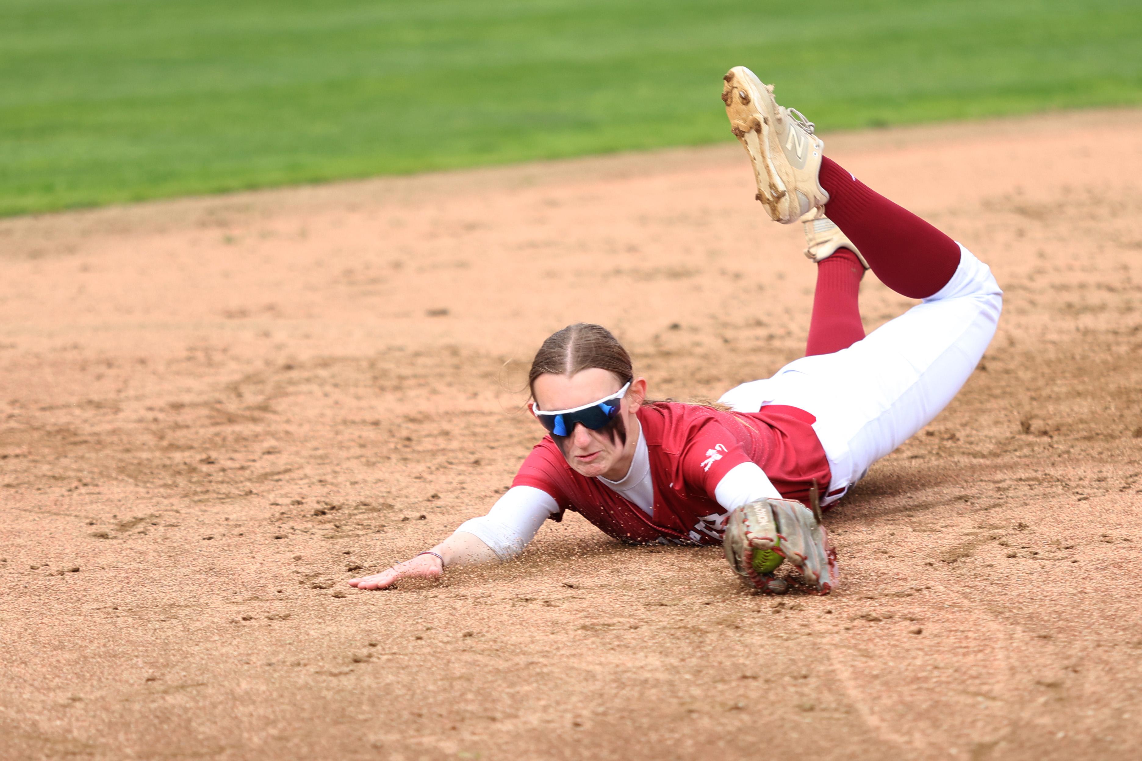 girl dives for softball in the dirt