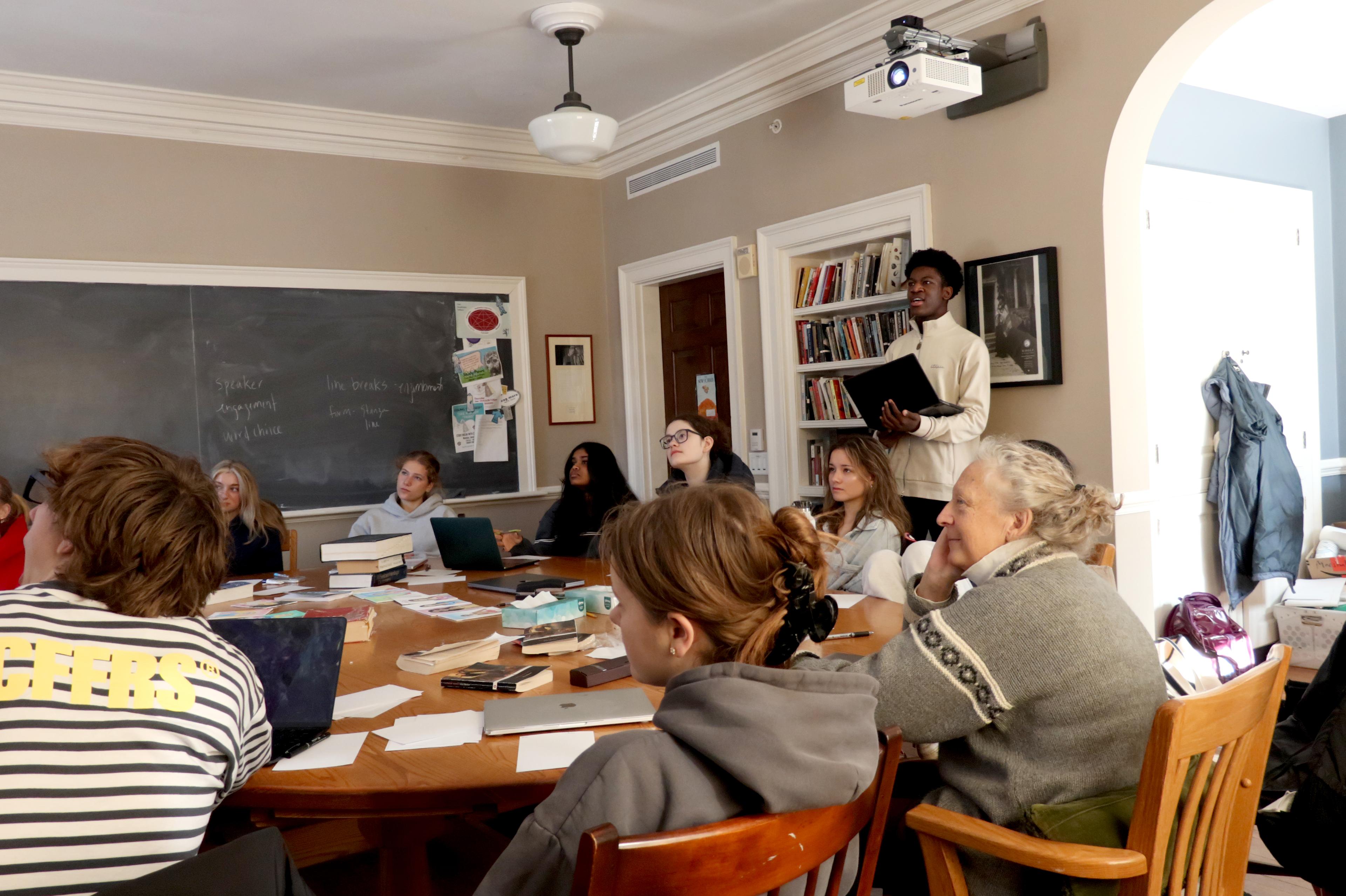 Student stands and present to peers around harkness table