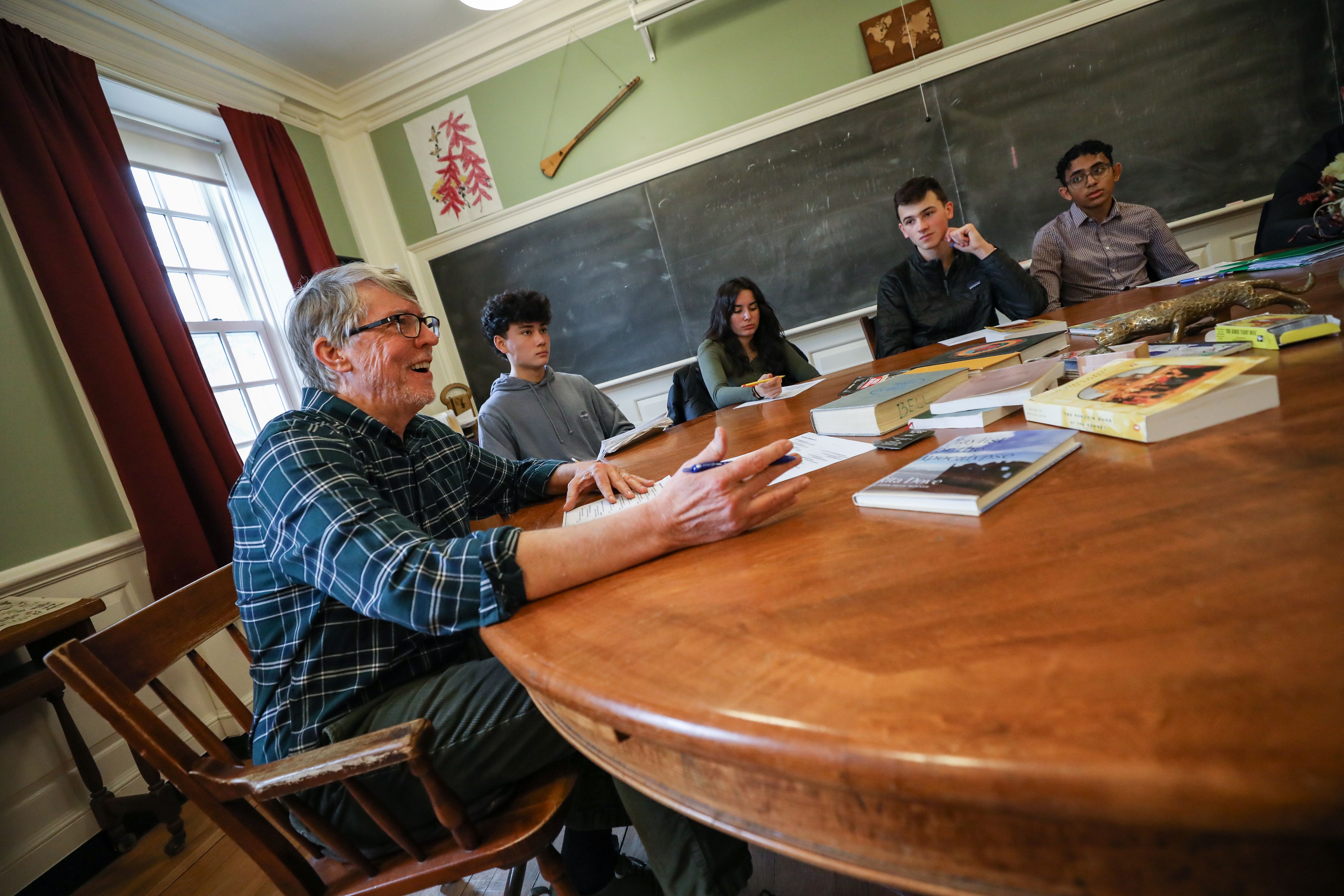 A teacher sits at a Harkness table.