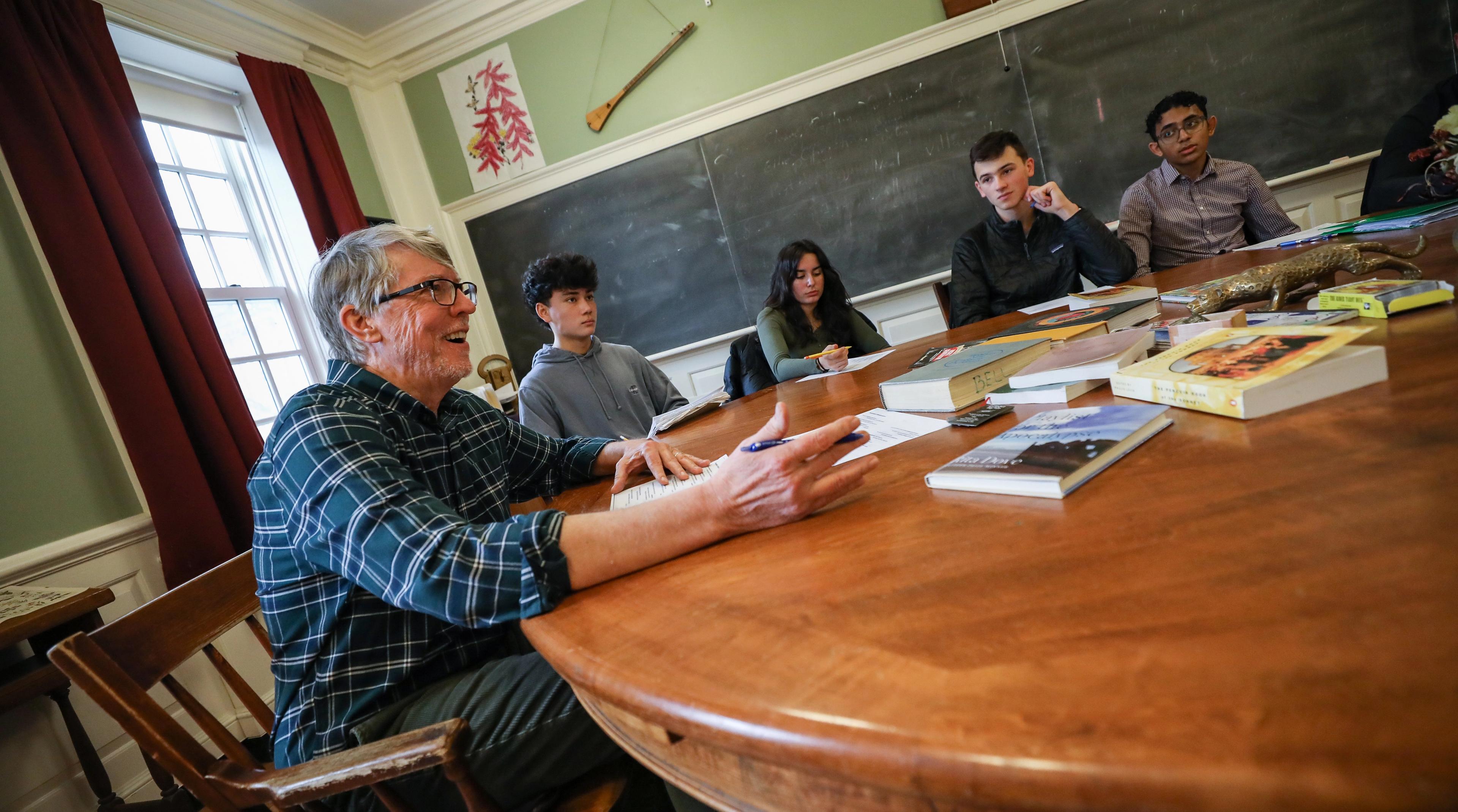 A teacher sits at a Harkness table.