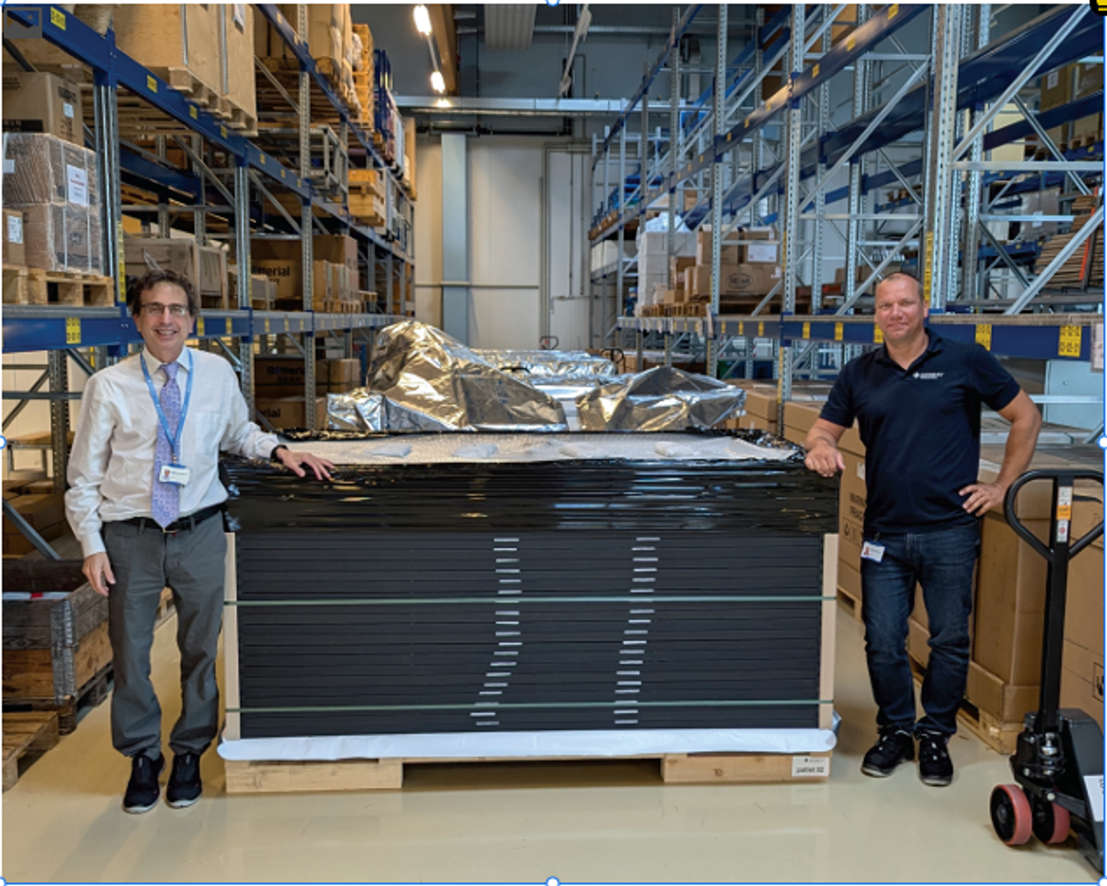 Chris Case standing next to a stack of solar panels