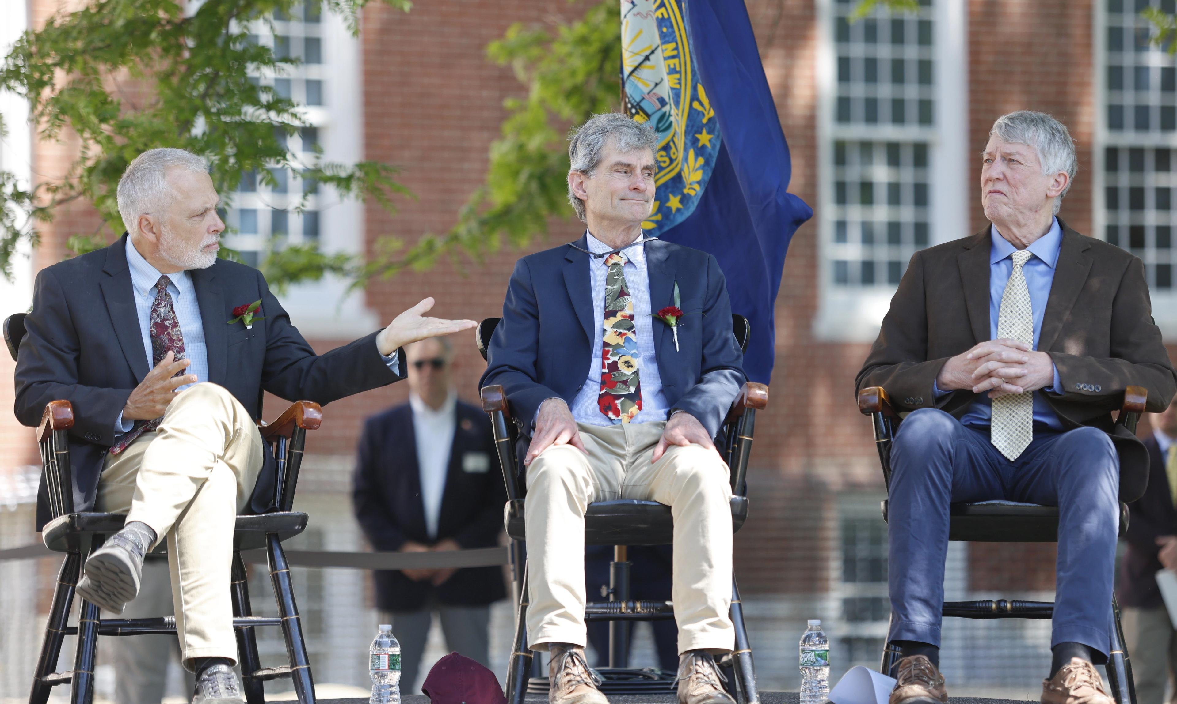 Three teachers sit on commencement stage