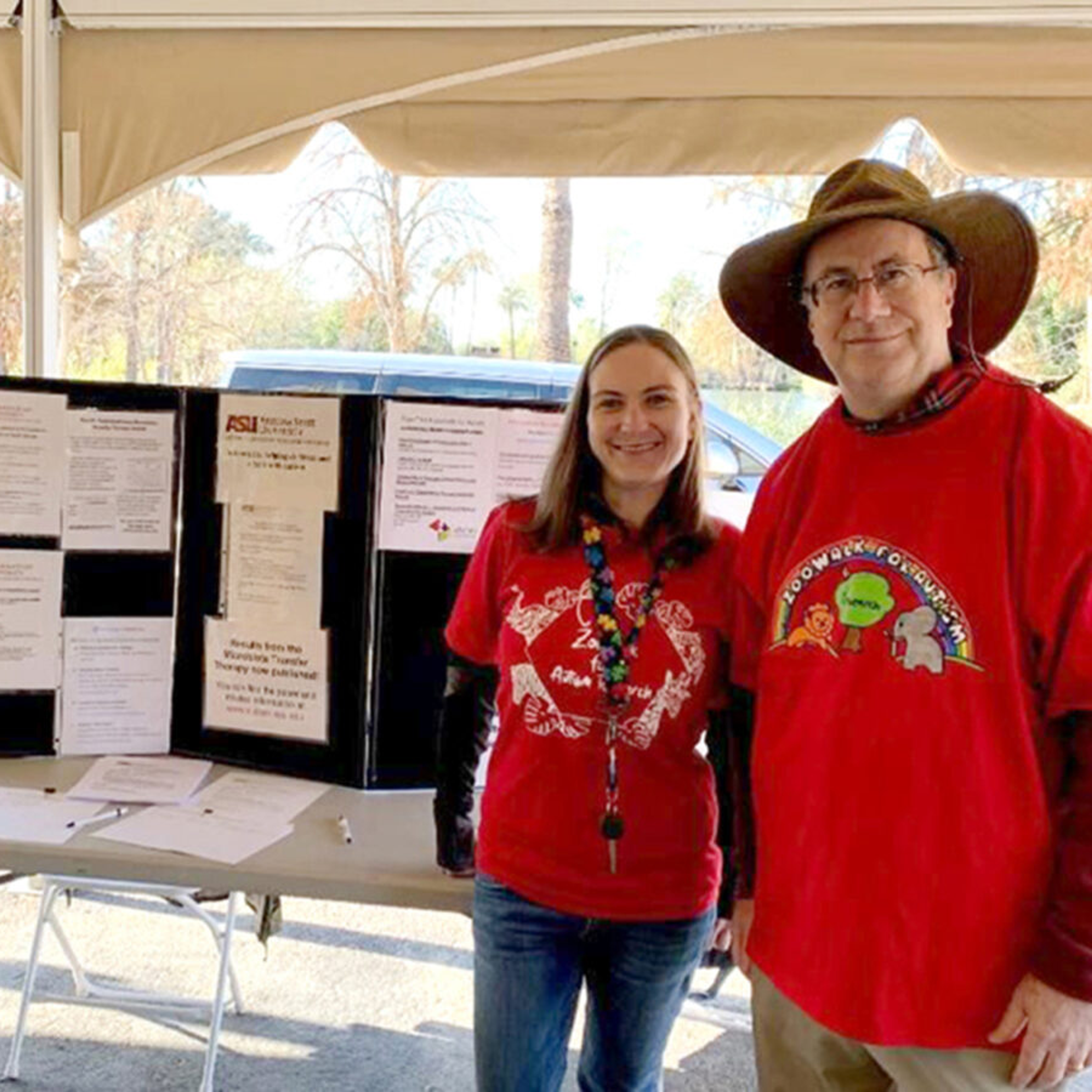 Three people stand in front of a table with a trifold poster board
