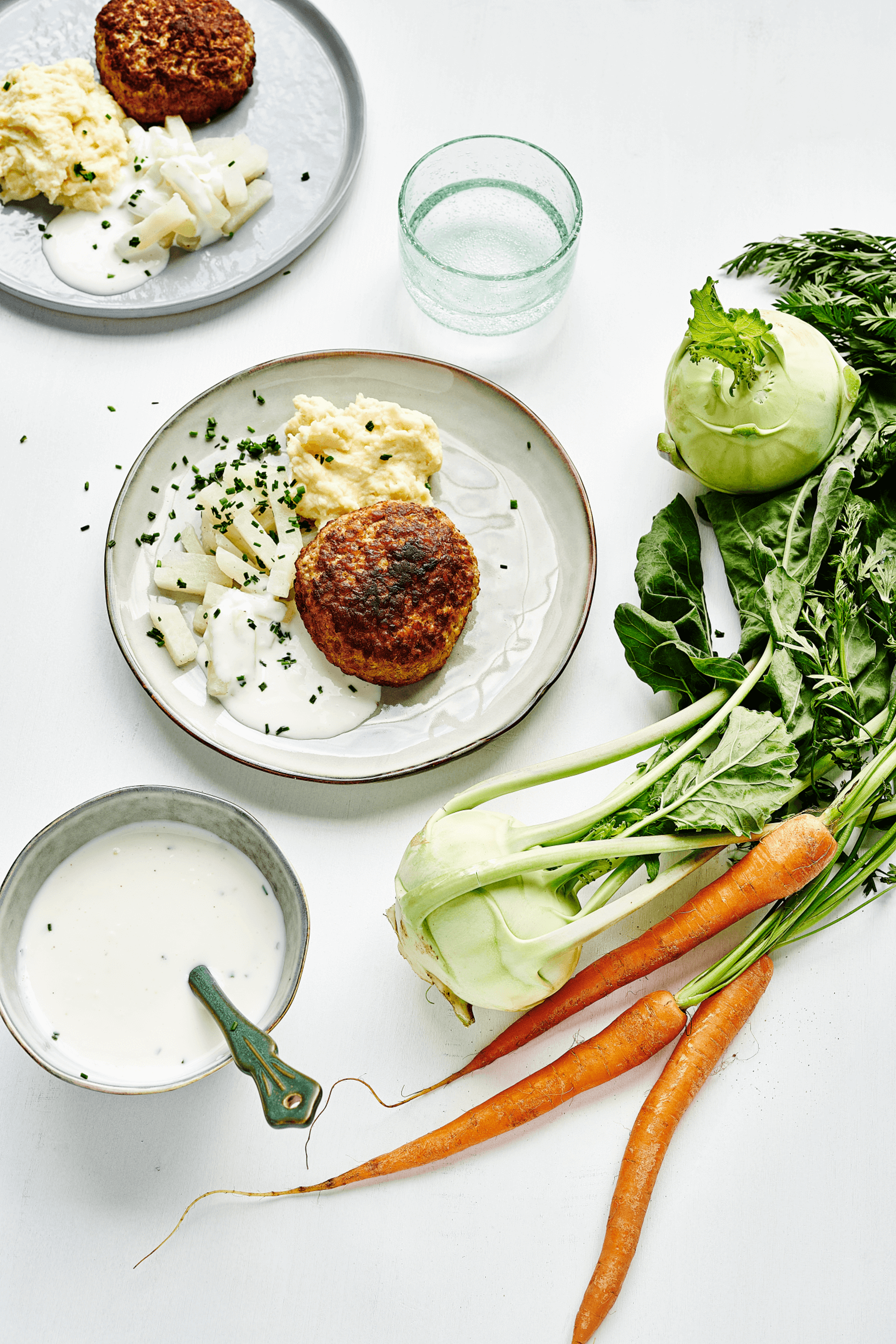 Eine köstliche Mahlzeit bestehend aus Kartoffelpüree, einer Gemüsefrikadelle, Kohlrabi und einer leckeren Joghurtsoße. Diese Speise ist Teil des abwechslungsreichen 10-wöchigen Menüplans von min food.