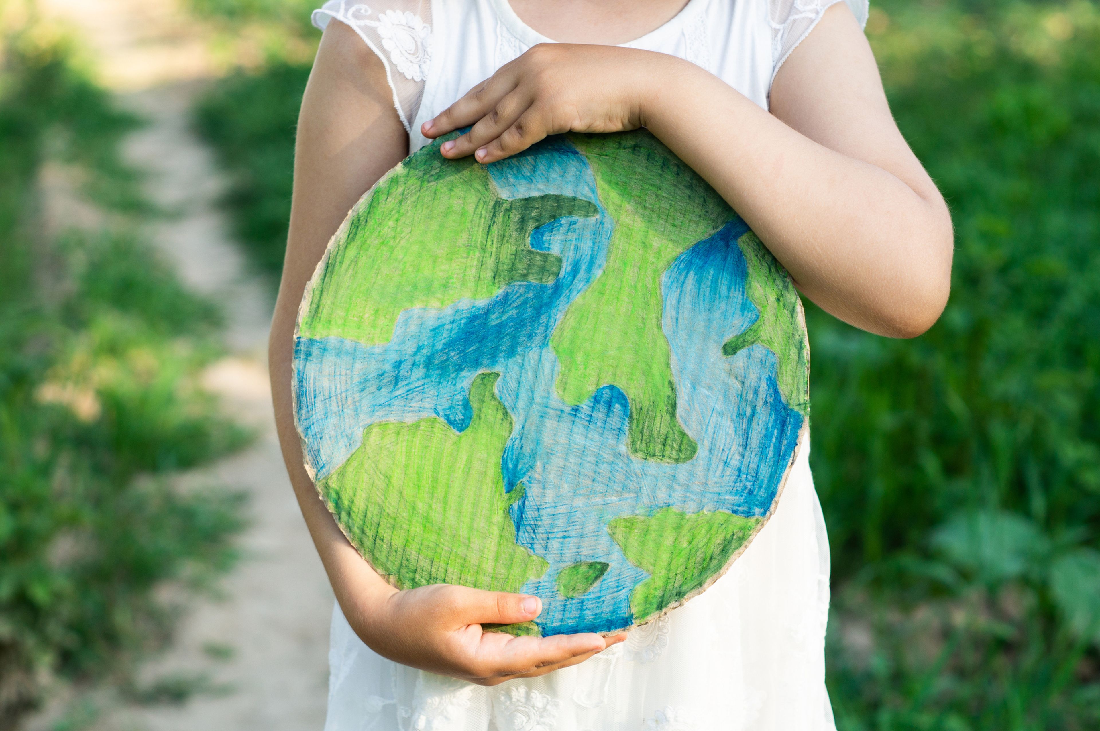Kind umschließt Zeichnung der Erde mit beiden Händen. min food setzt sich mit Kindern aus ganz Aachen für ein friedvolles Zusammenleben auf der ganzen Welt ein. 