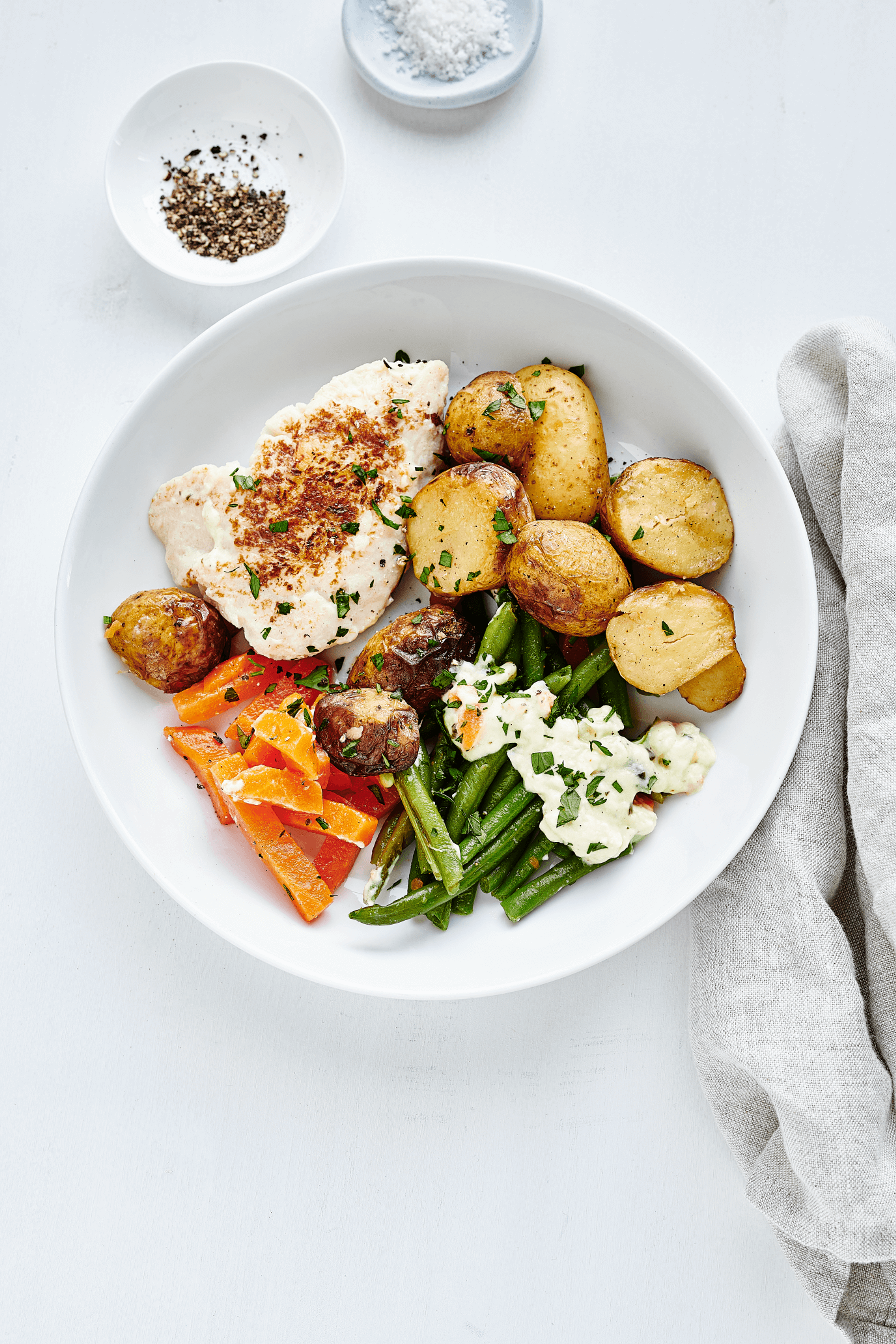 Ein leckerer Teller mit Kartoffeln, Spiegelei, Bohnen und Möhren, Teil des vielfältigen 10-wöchigen Menüplans von min food für Bistro und Unternehmensverpflegung.