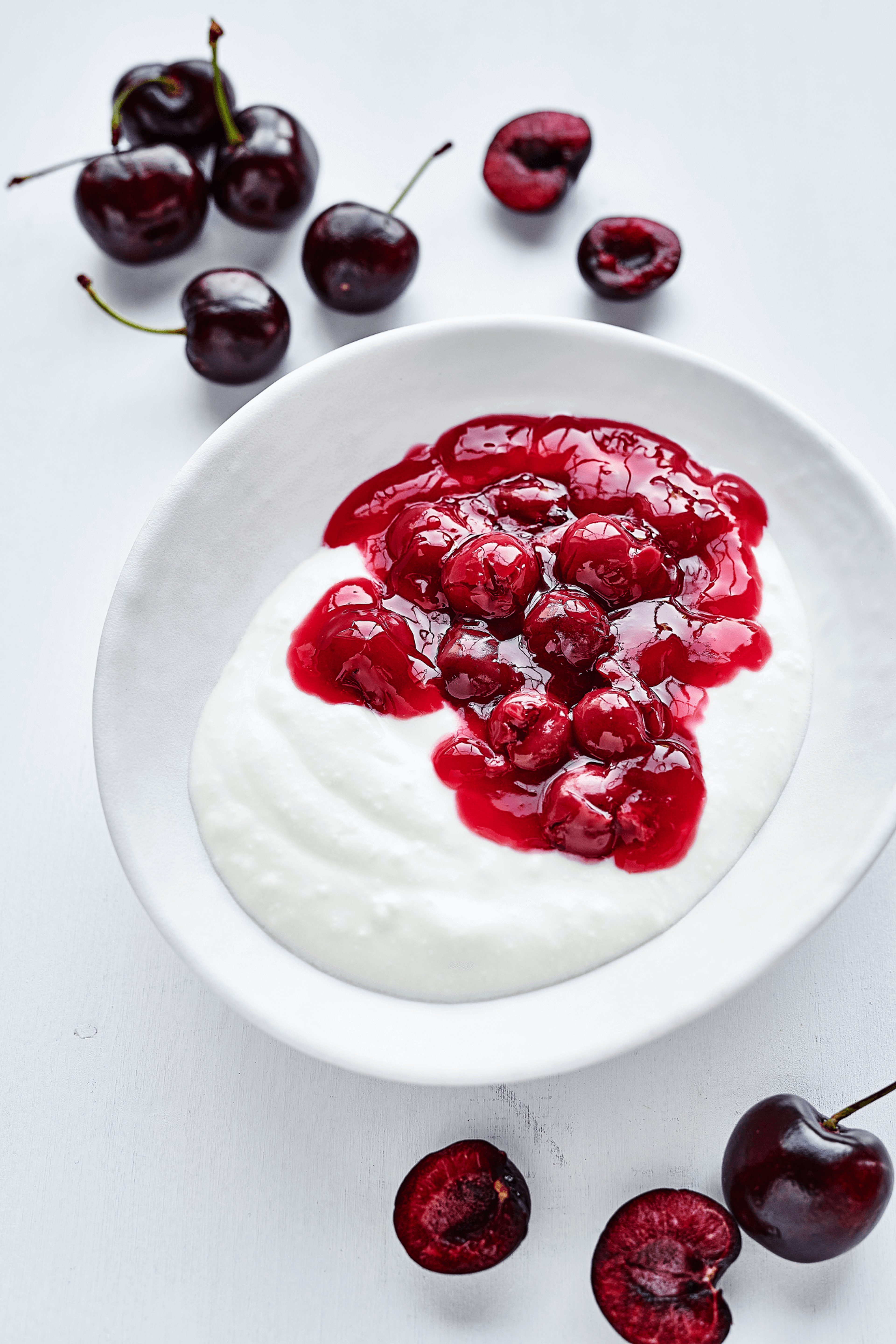 Eine köstliche Schüssel Joghurt mit einer reichhaltigen roten Kirschgrütze und saftigen Kirschen, Teil des 10-wöchigen Menüplans von min food für Schulen und Kitas.