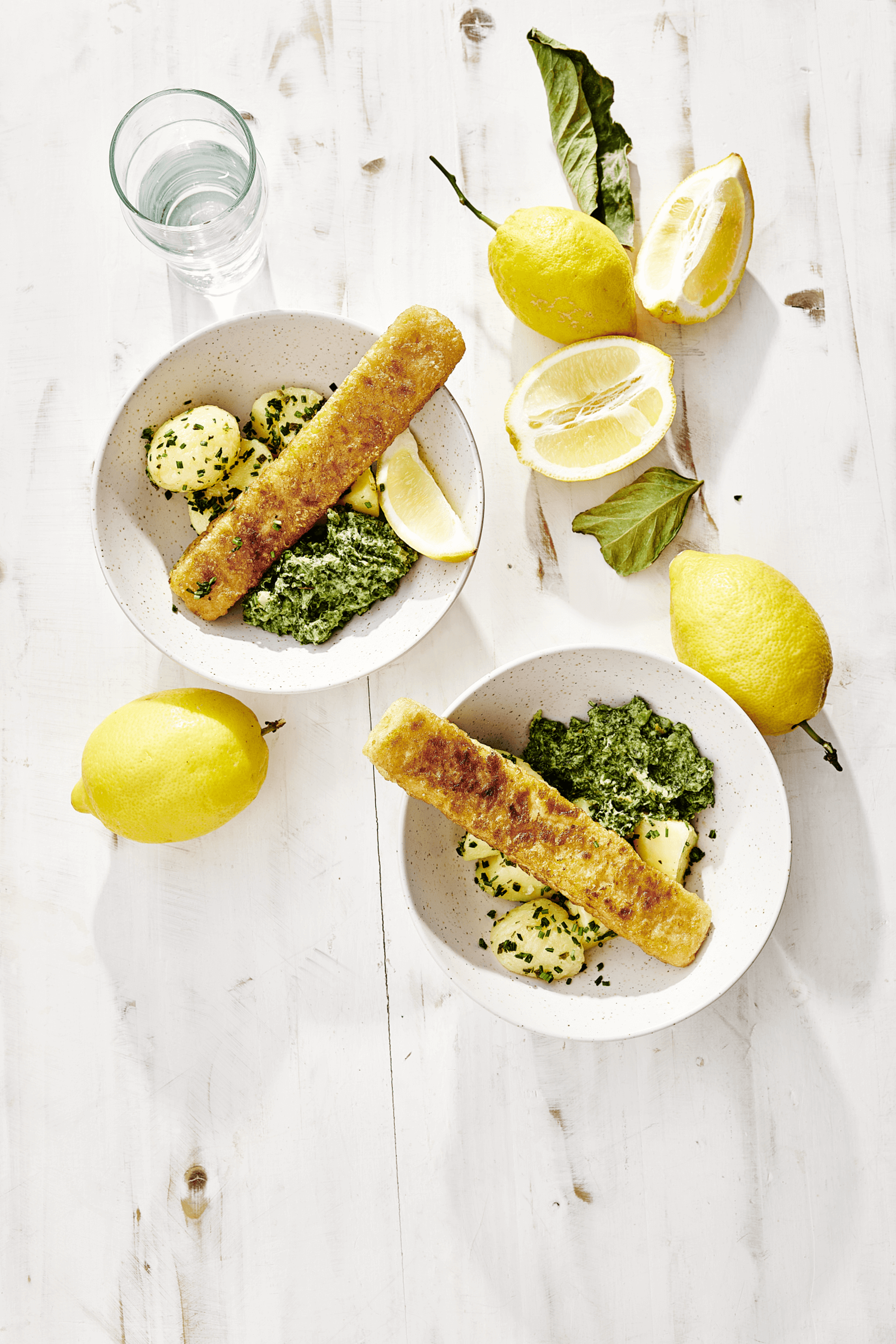 Zwei köstliche Teller mit Jumbofischstäbchen, Kartoffeln und Spinat, Teil des abwechslungsreichen 10-wöchigen Menüplans der min food für Schulen und Kitas.