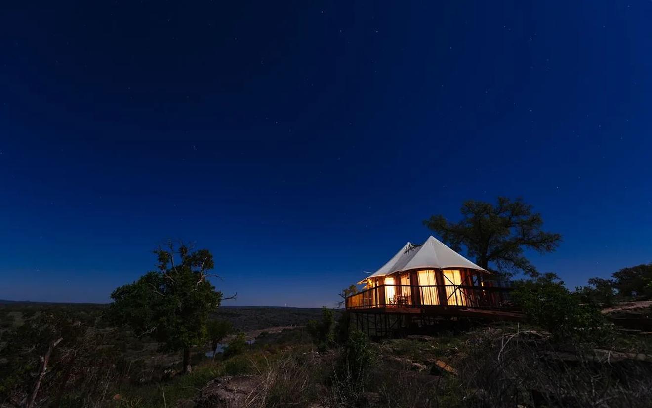 Lit canvas tent suite on a bluff under a starry sky at Walden Retreats, a Johnson City Hill Country wedding venue