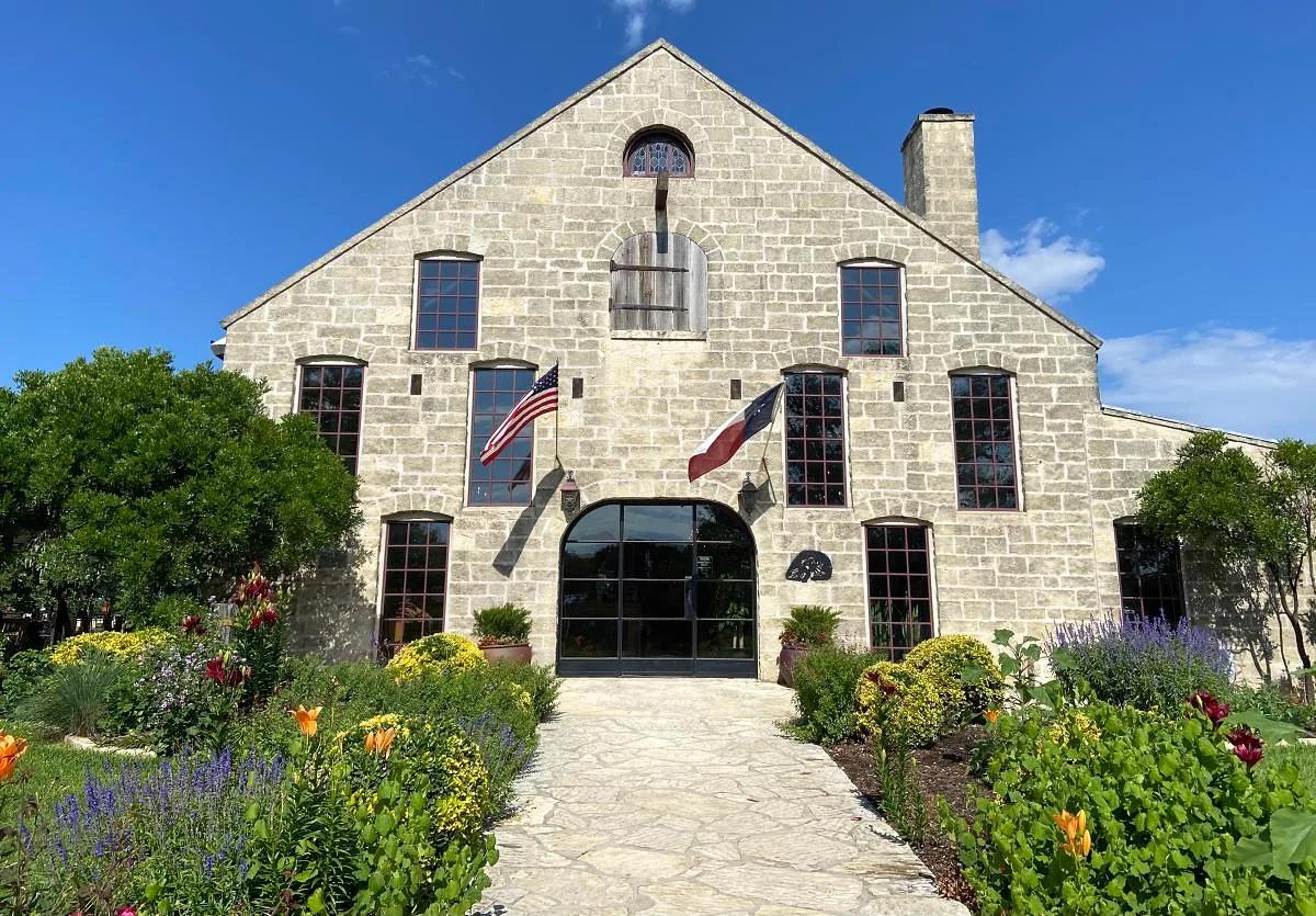 Stone winery building and spring flower gardens at Becker Vineyards, a Fredericksburg, Texas winery on Highway 290