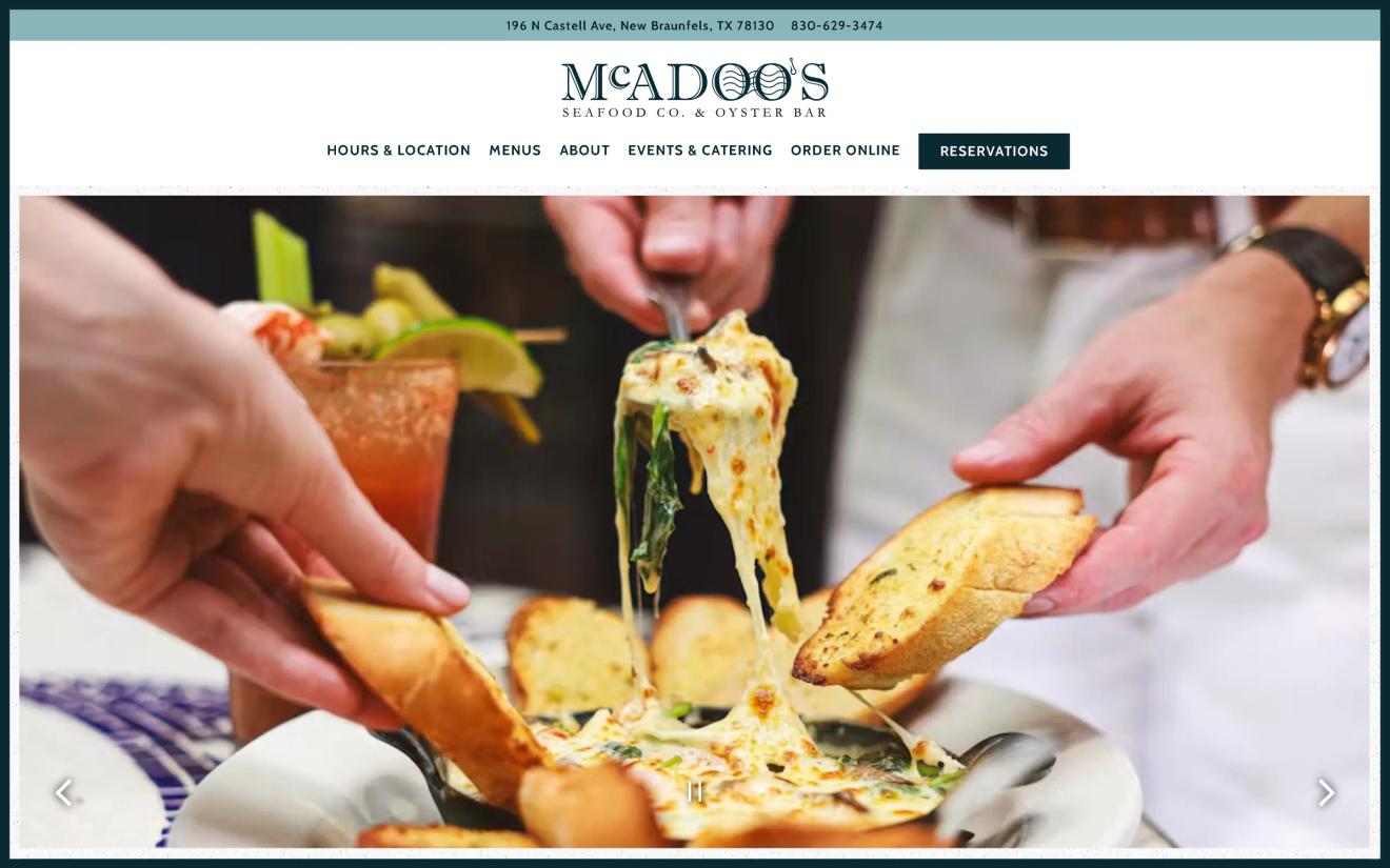 Hands dipping garlic bread into cheesy seafood dip at McAdoo's Seafood Co. and Oyster Bar