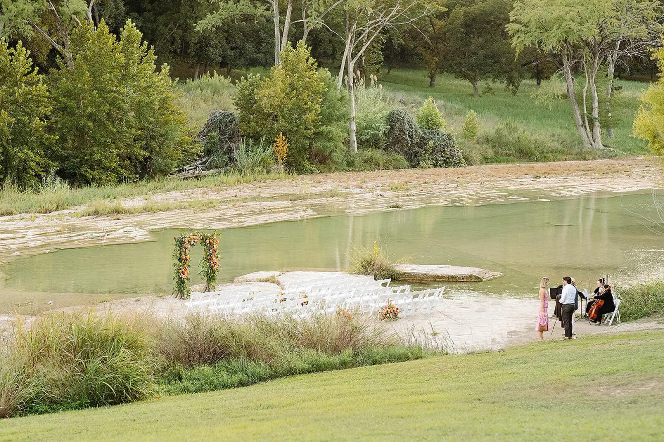 Riverside ceremony seating on the rock shelf of the Blanco River at The Waters Point, a Wimberley Hill Country wedding venue