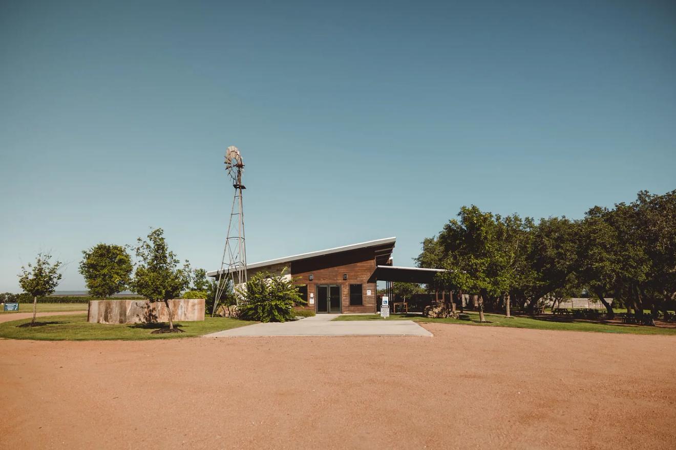 Wood tasting room and windmill under open sky at Ab Astris Winery in Stonewall, near Fredericksburg, Texas