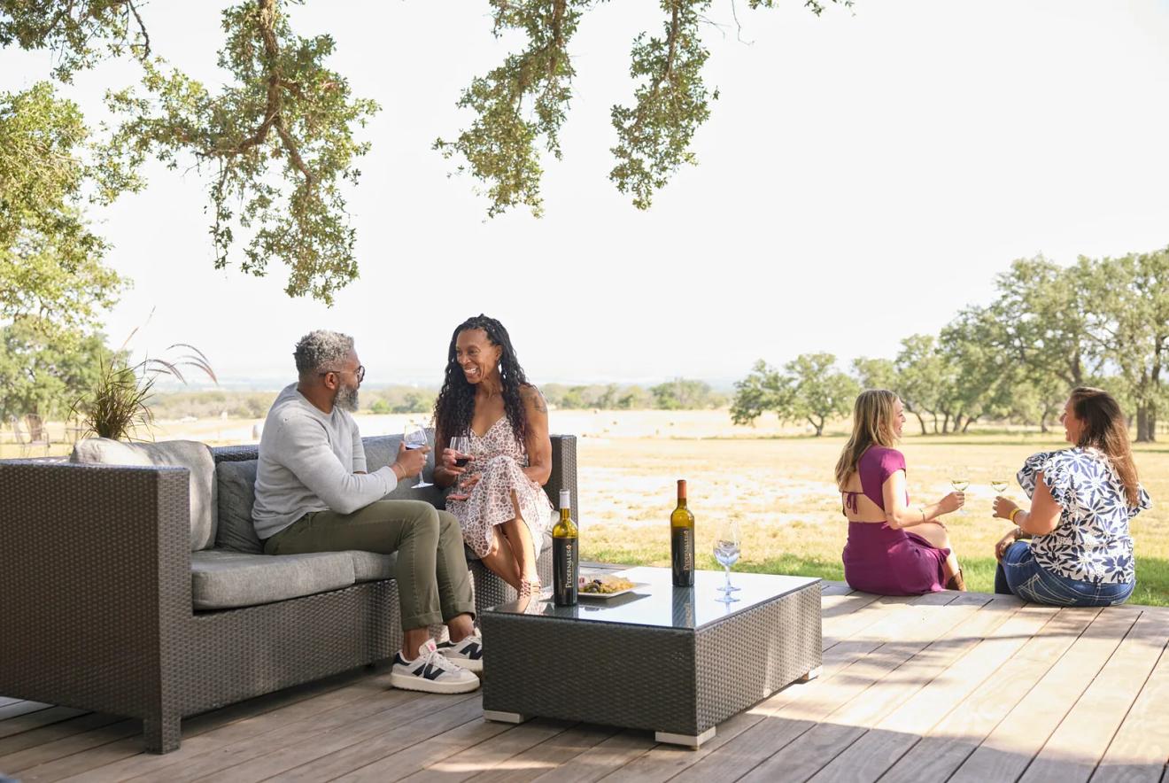 Guests on the oak-shaded tasting deck above the Pedernales River valley at Pedernales Cellars, one of the best wineries near Fredericksburg, Texas