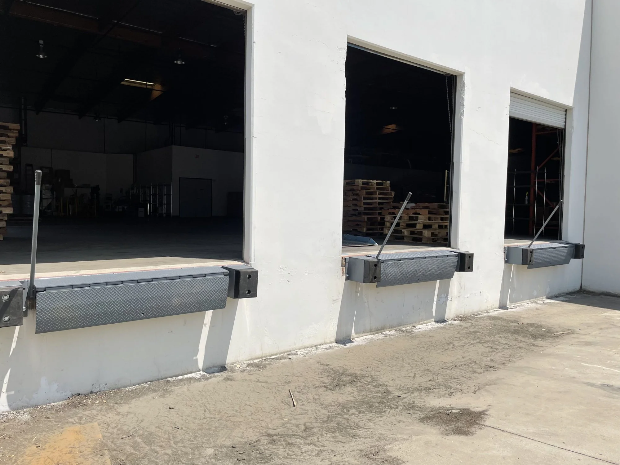 Commercial warehouse loading dock with three mechanical dock levelers and open bay doors