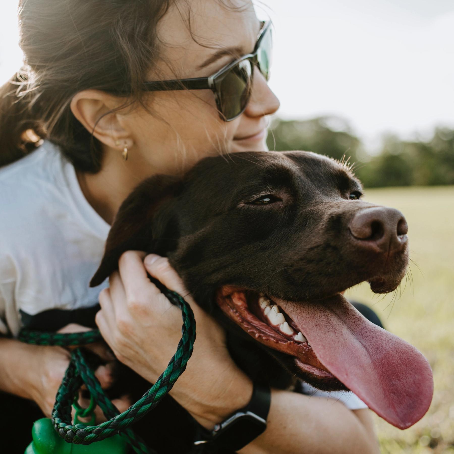 Dame med solbriller og hund som smiler
