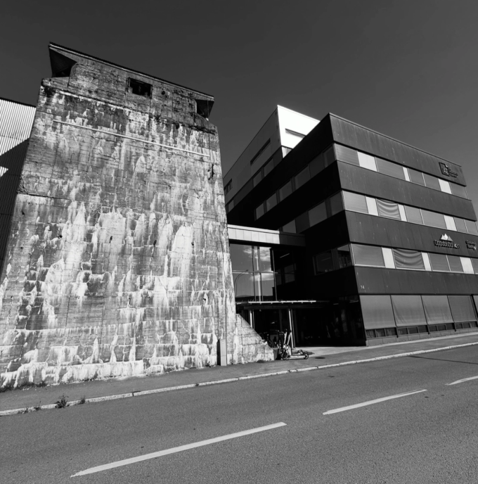 The Nonspace office in Trondheim, located in a modern waterfront building with the historic Dora II concrete wall integrated into the entrance.