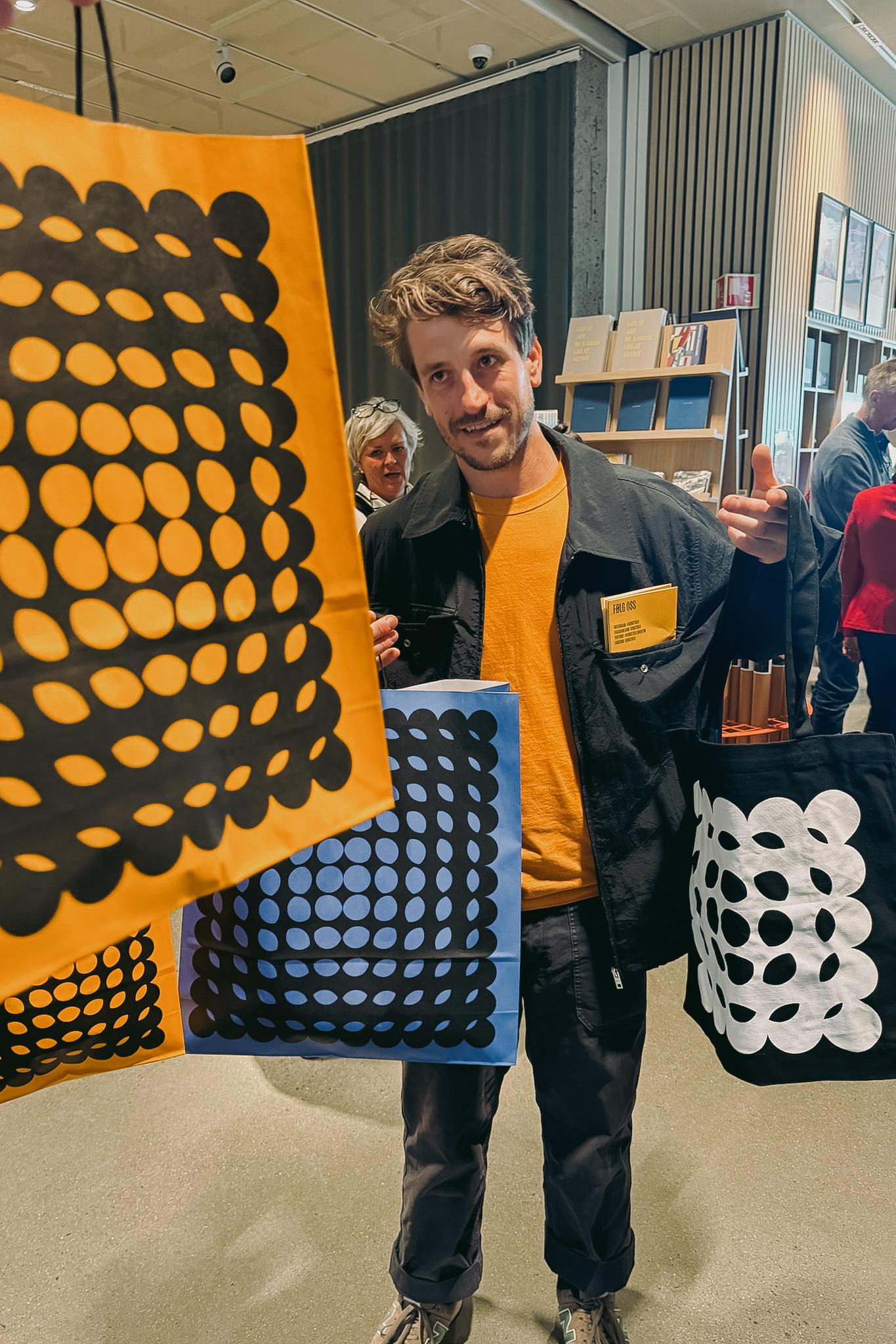 Mark Trzopek at Kunstsilo holding Kunstsilo tote bags