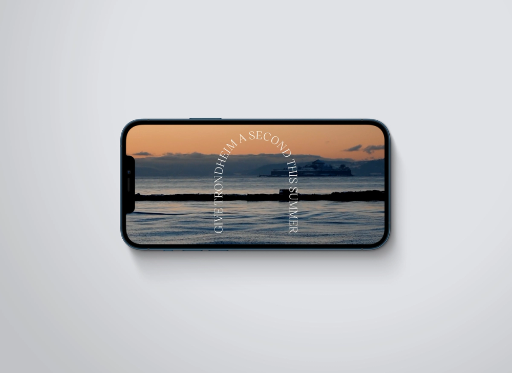 A smartphone displaying a sunset coastal scene with curved text reading "Give Trondheim a second this summer" — by Nonspace