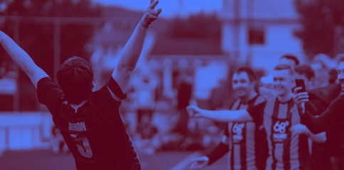 A soccer player named Jeron with arms raised celebrates toward cheering fans in the stands — by Nonspace