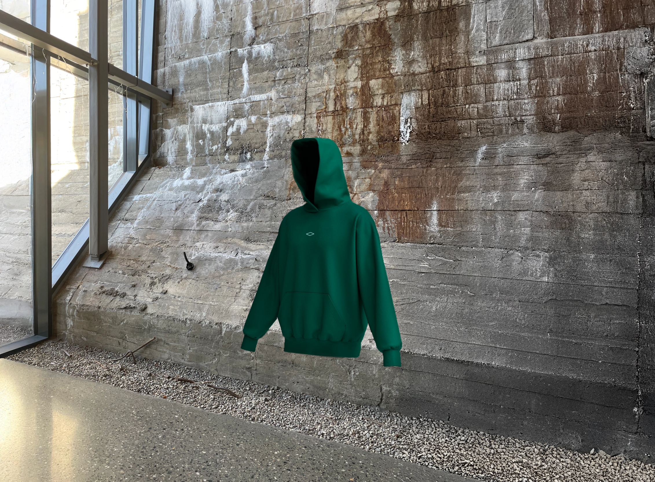 En grønn hettegenser med et lite diamantlogo svever foran en rustikk betongvegg i et industrielt rom — av Nonspace