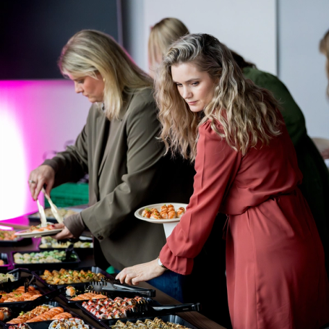 To kvinner forsyner seg fra et sushi-buffetbord under et arrangement for kvinner på tvers av bransjer — av Nonspace