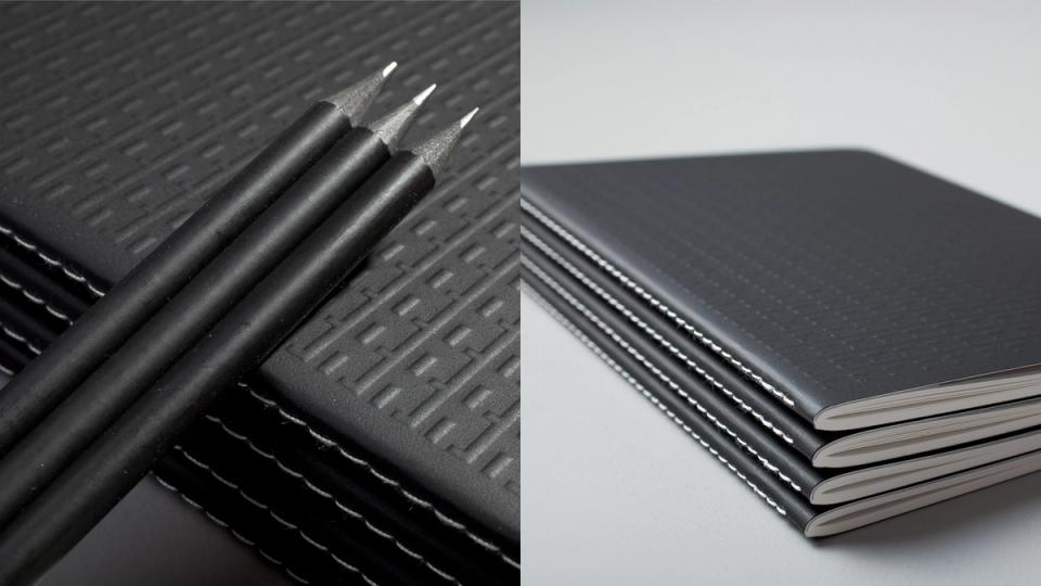 Three black pencils resting on dark notebooks with embossed geometric patterns and visible spine stitching — by Nonspace