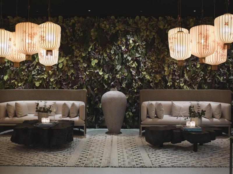 Loungeområde med to sofaer, plantevegg, papirlamper og en stor vase i Britannia Spa & Fitness — av Nonspace