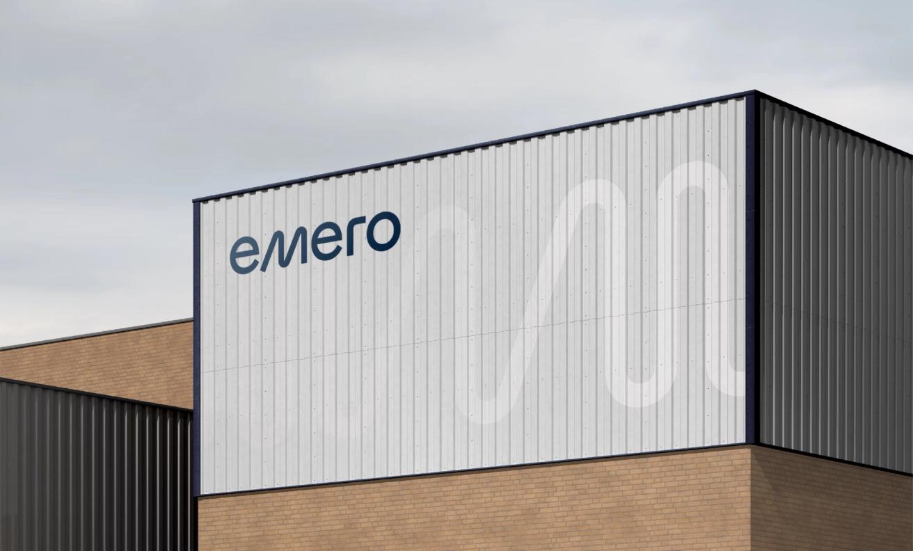 Emero company logo displayed on a white corrugated metal industrial building facade — by Nonspace