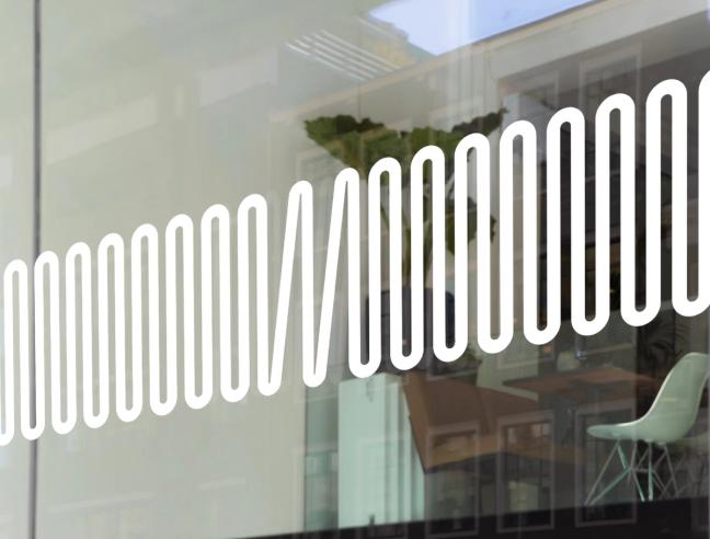 A white wave-like logo design on a glass window of a modern office space with reflections visible — by Nonspace
