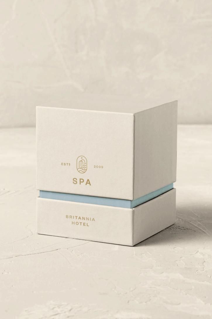 To stablede esker med Britannia Hotel Spa-branding i beige og lyseblått på en lys teksturert bakgrunn — av Nonspace