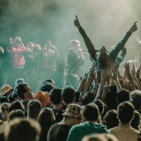 A vibrant concert scene with a crowd surfer and lively audience members enjoying a live performance