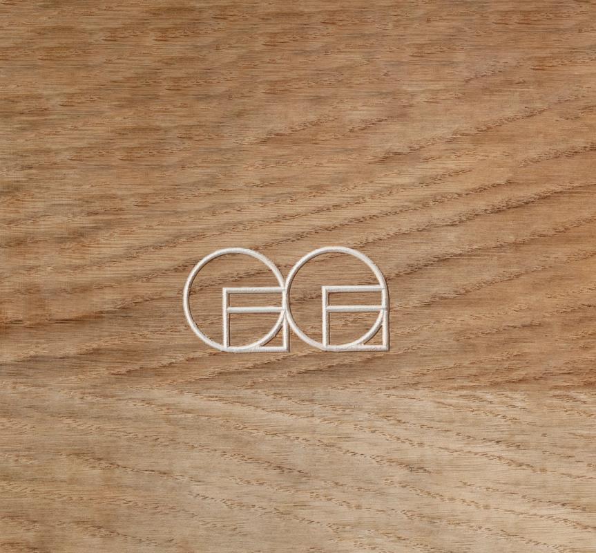 En logo med to overlappende sirkler og geometriske former preget inn i en treoverflate — av Nonspace