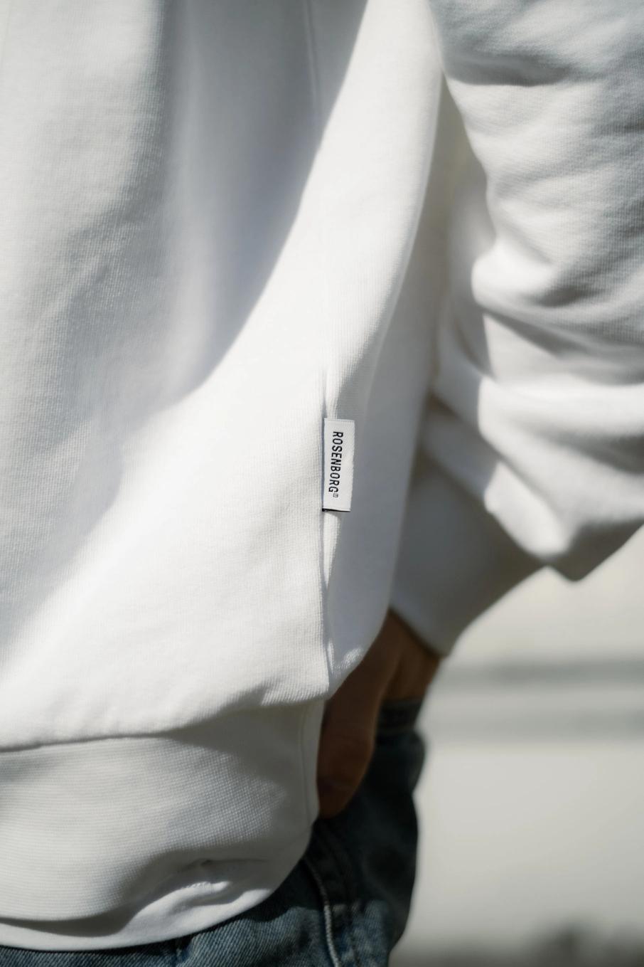 En person i hvit genser med Rosenborg-merke på siden og blå jeans — av Nonspace